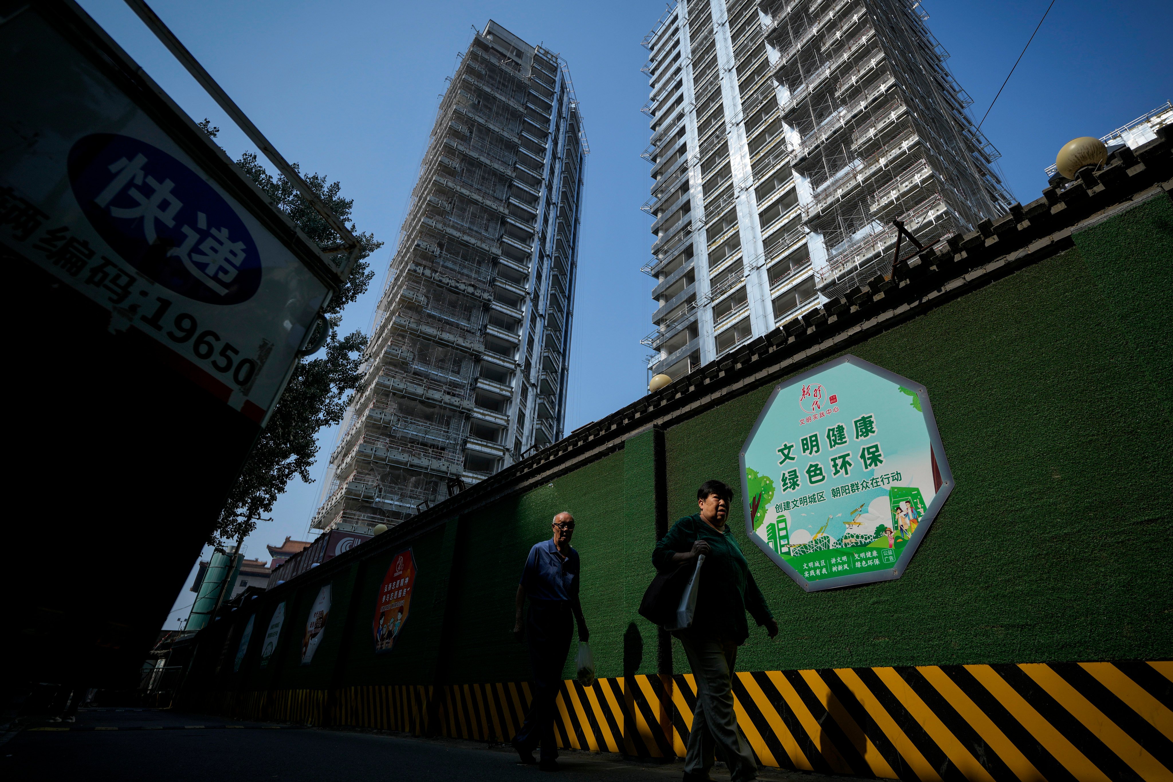 Residents walk by a luxury housing construction site in Beijing. Photo: AP