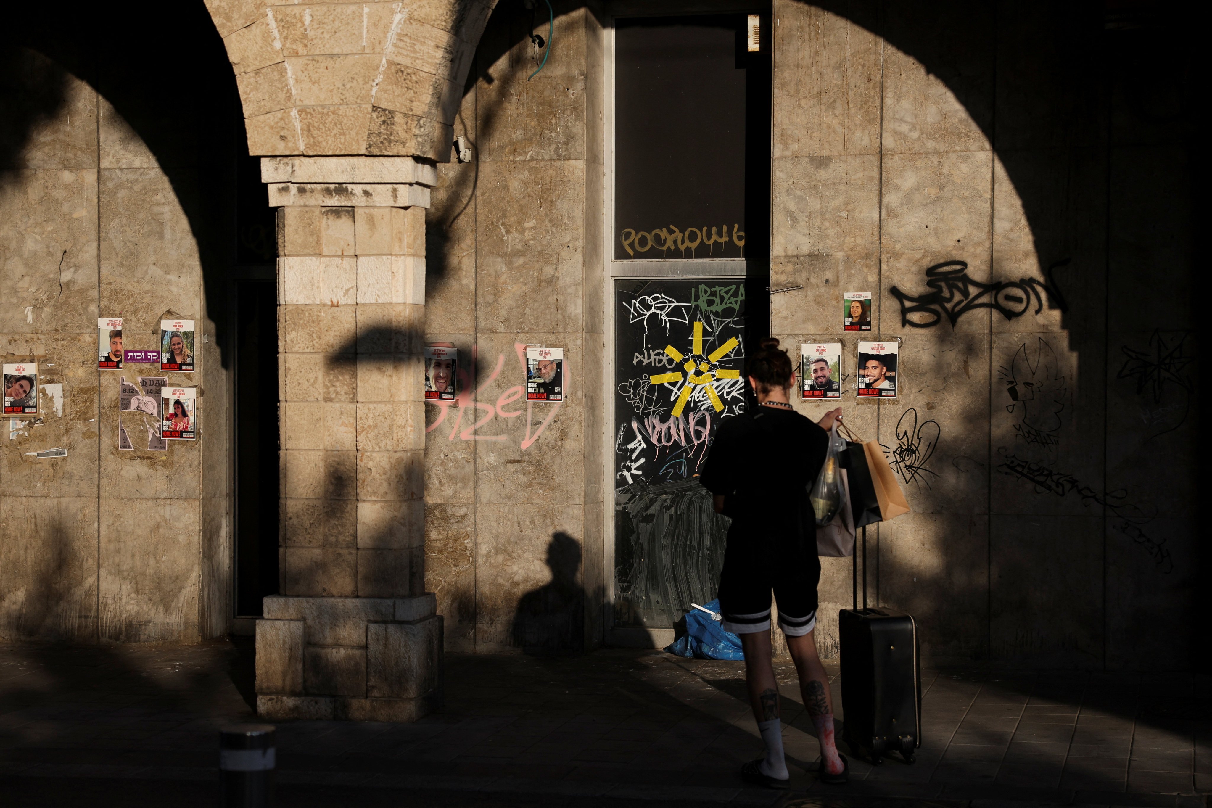 A person stands next to the posters with the images of people kidnapped during the deadly October 7, 2023 attack by Hamas, in Jaffa, Israel, on October 17. Photo: Reuters