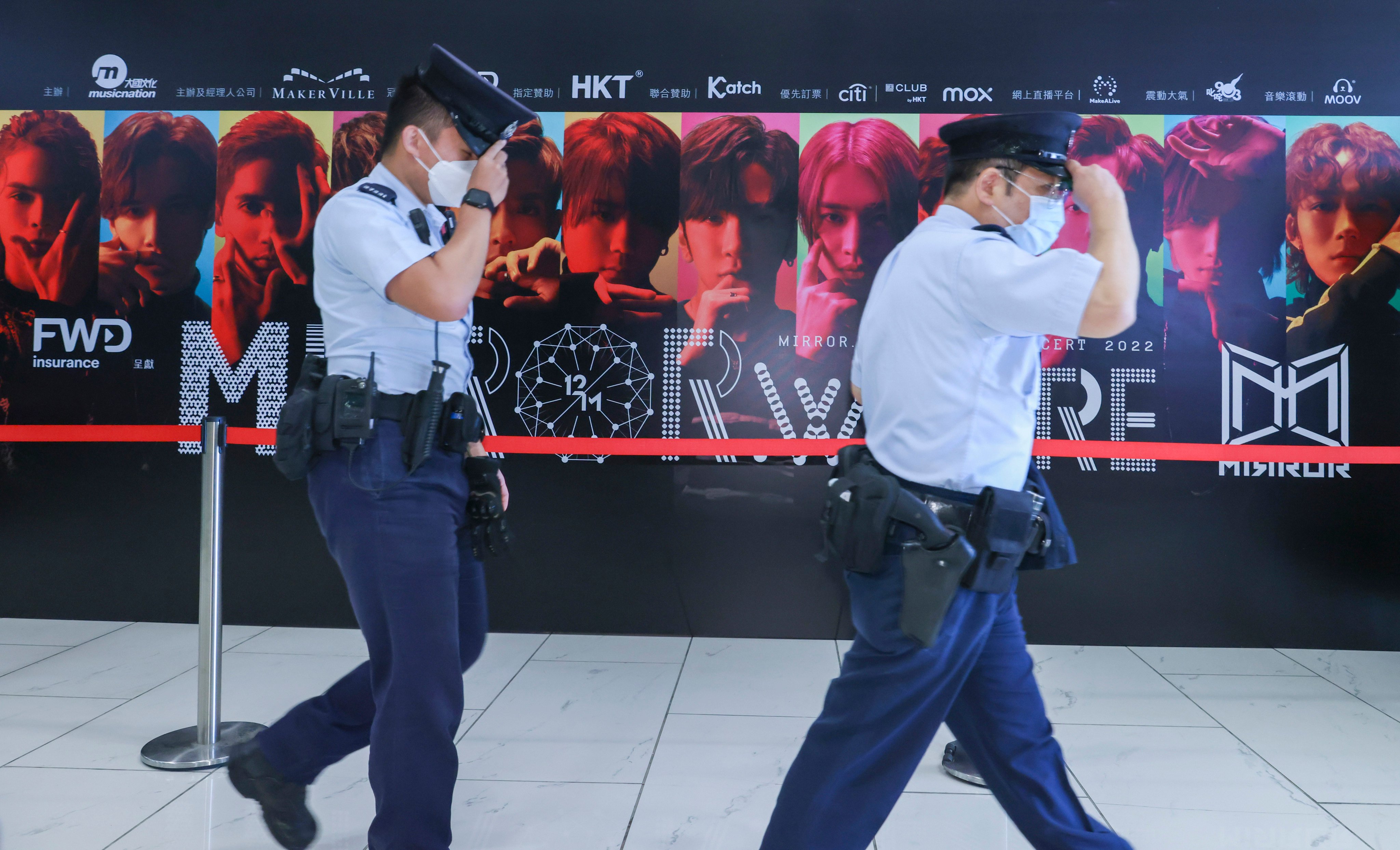 Security officers walk past a display promoting Cantopop boy band Mirror. Photo: Dickson Lee