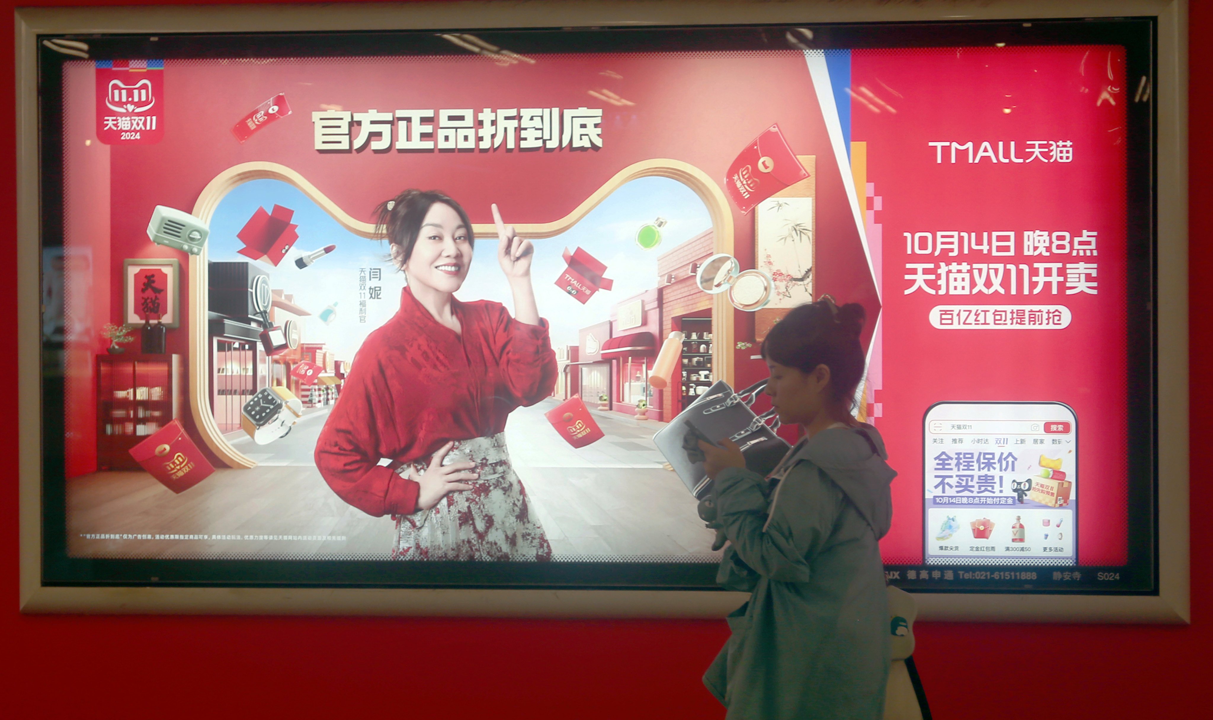 A woman walks past a Singles’ Day shopping festival ad displayed on an LCD screen in Shanghai, October 15, 2024. Photo: VCG