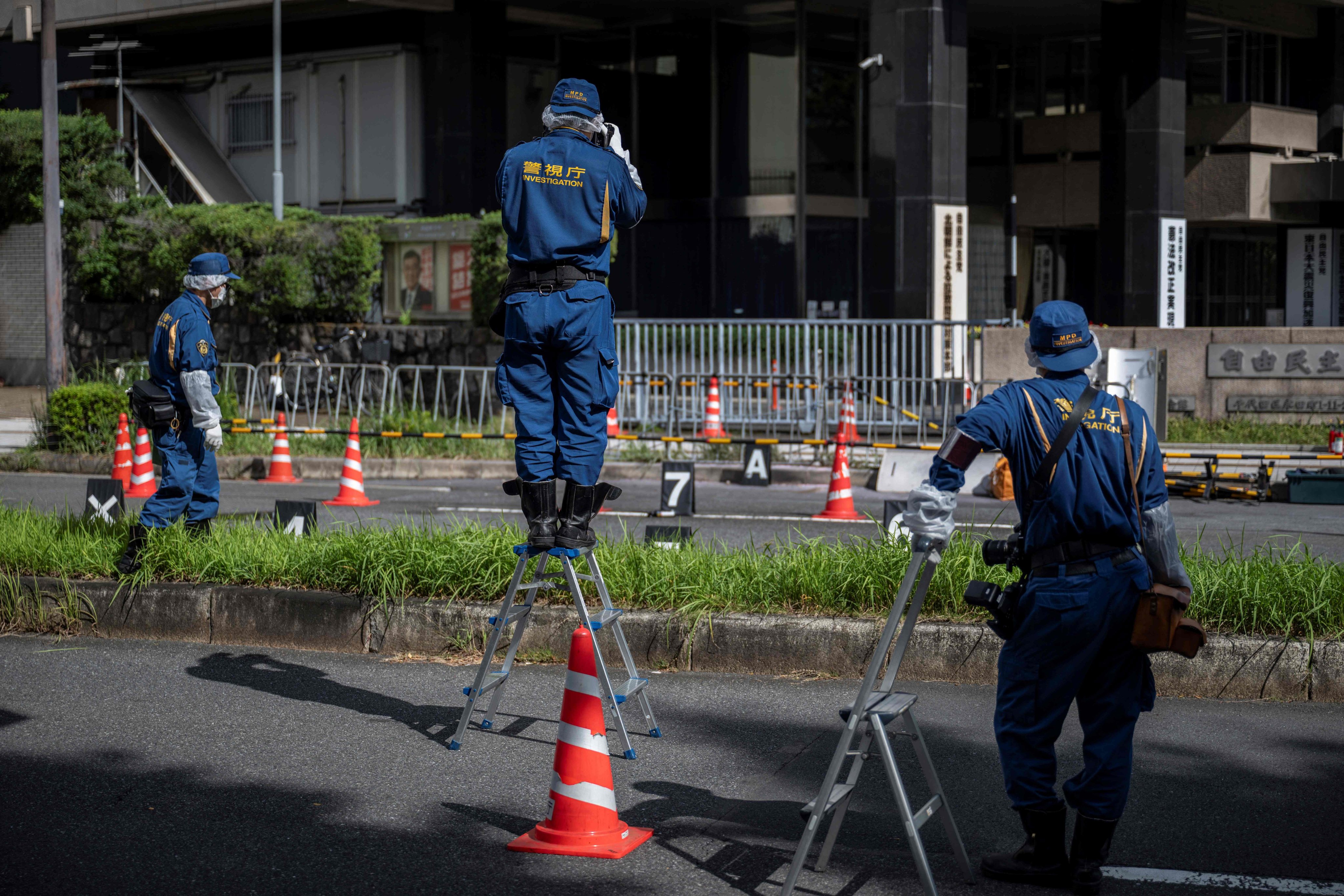 Police officers investigate the scene outside the ruling Liberal Democratic Party headquarters in central Tokyo on Saturday after a man threw Molotov cocktail-like objects outside the building. Photo: AFP