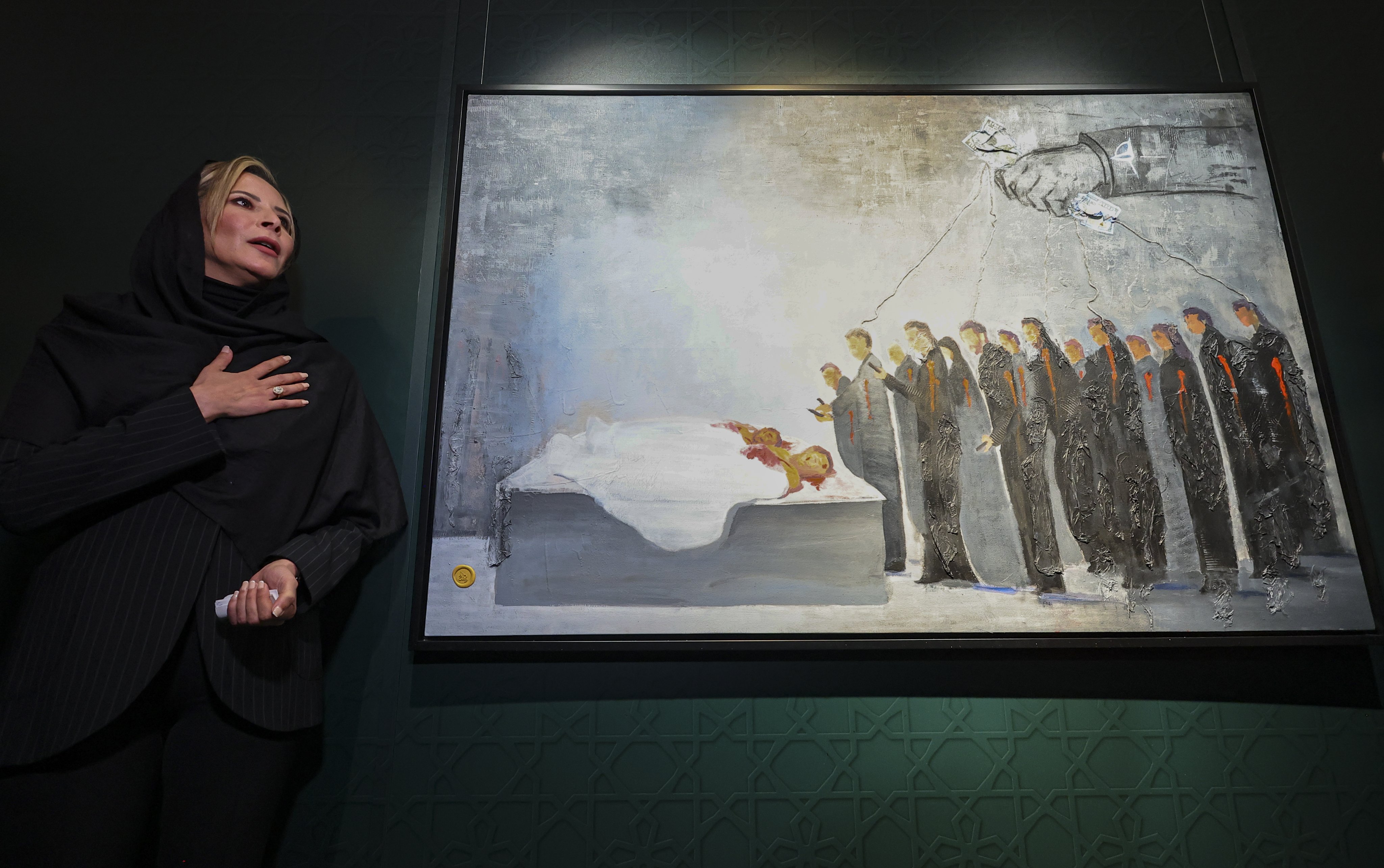 Aisha Gaddafi, daughter of slain Libyan leader Muammar Gaddafi, presents one of her paintings showing a crowd hovering over the corpses of her father and her brother at the State Museum of Oriental Art in Moscow, which is mounting a show of her art. Photo: EPA-EFE