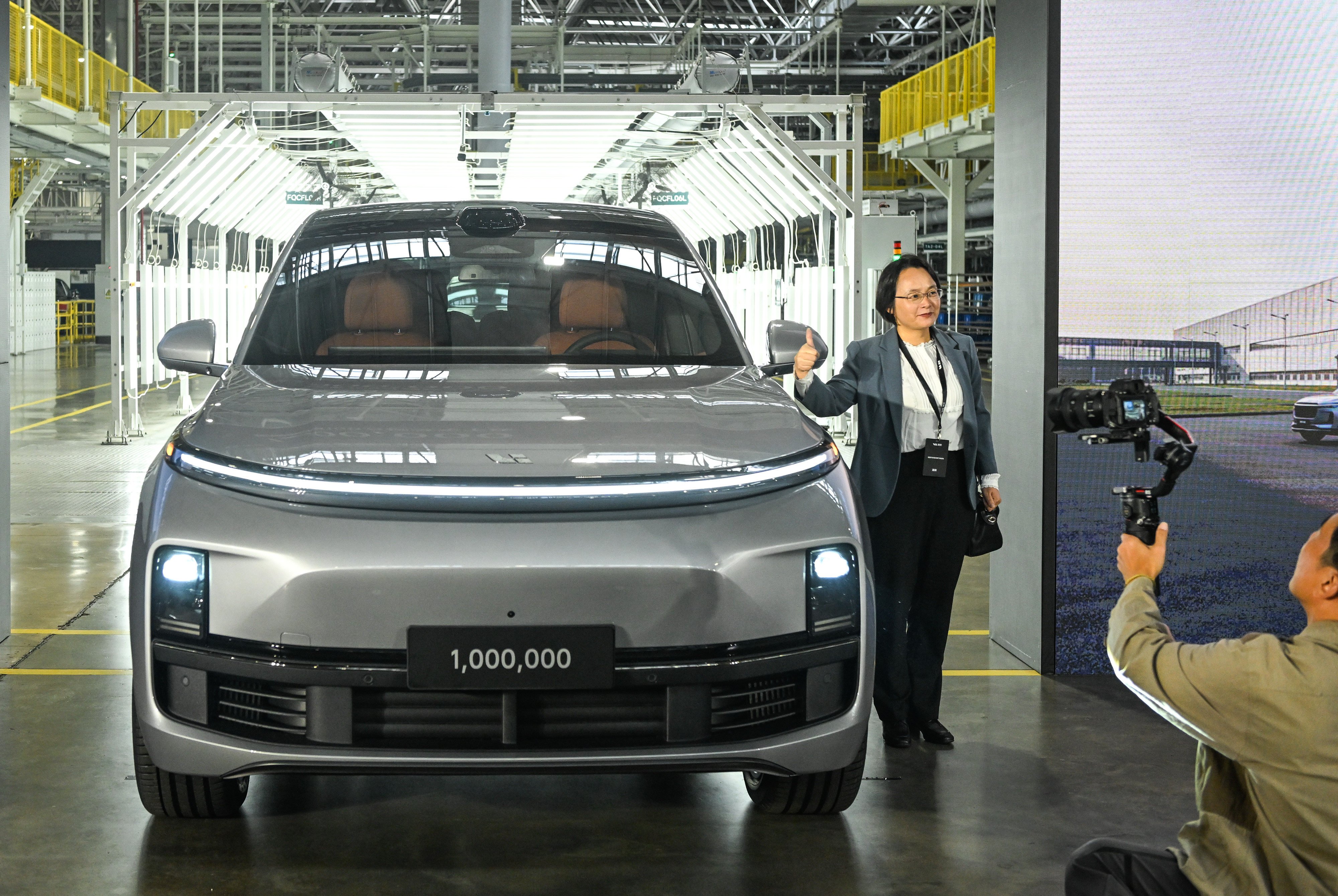 A guest poses for photos with Chinese carmaker Li Auto’s 1 millionth vehicle during a roll-off ceremony in Changzhou on October 14. Photo: Xinhua