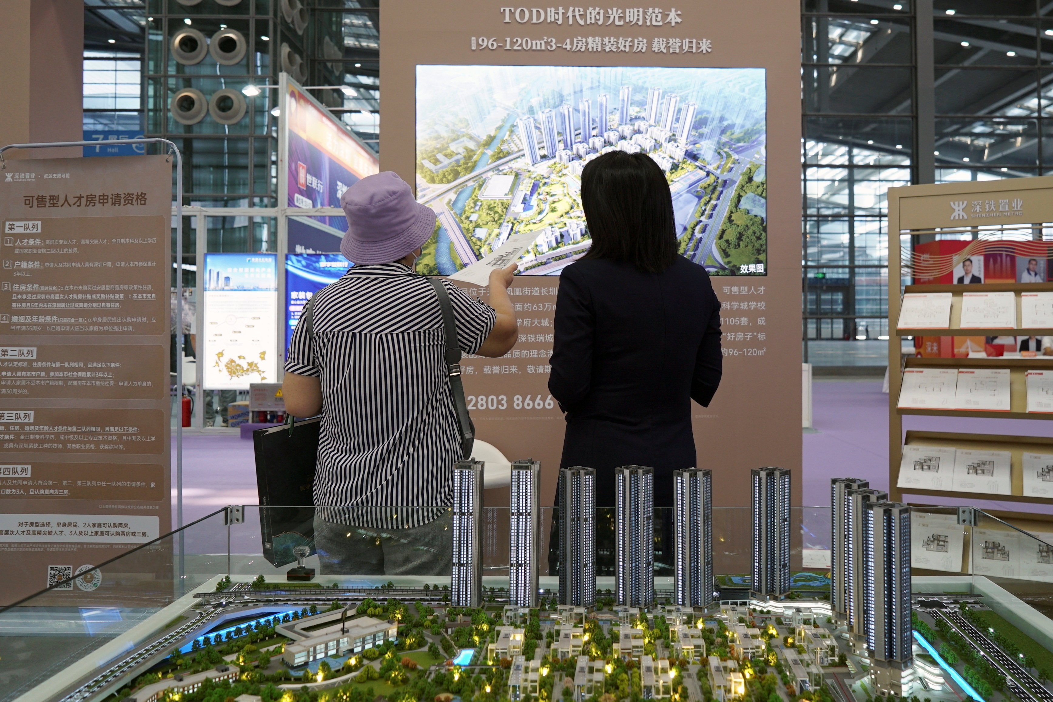 An agent attends to a customer near a scale model of residential buildings at a property fair in Shenzhen, Guangdong province. Photo: Reuters