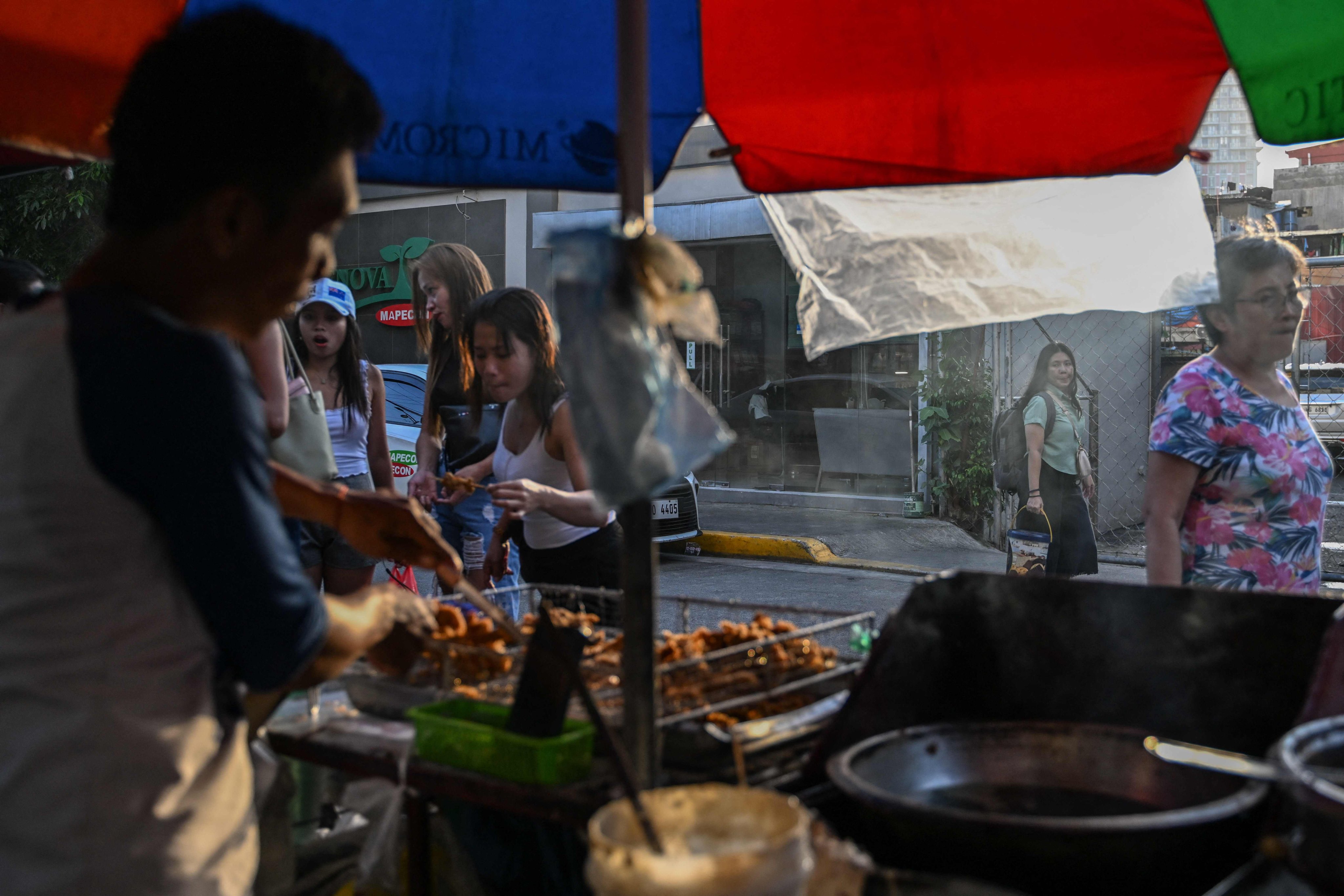 Filipinos look on as a vendor sells street food in Manila on Friday. Photo: AFP