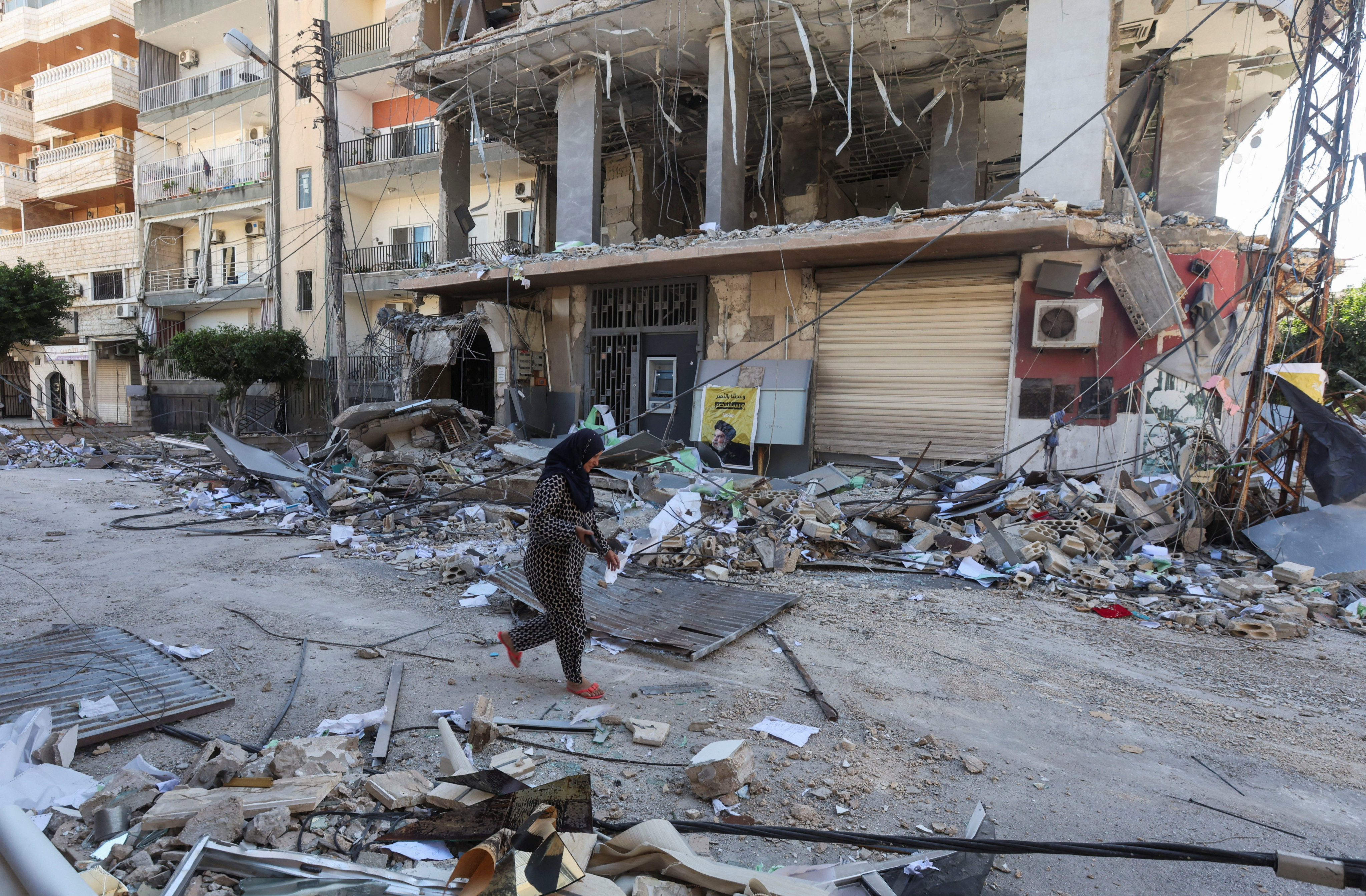 A woman walks past a damaged branch of Al-Qard al-Hassan, in the aftermath of Israeli airstrikes that hit several branches of the financial institution linked to Lebanon’s Hezbollah. Photo: Reuters