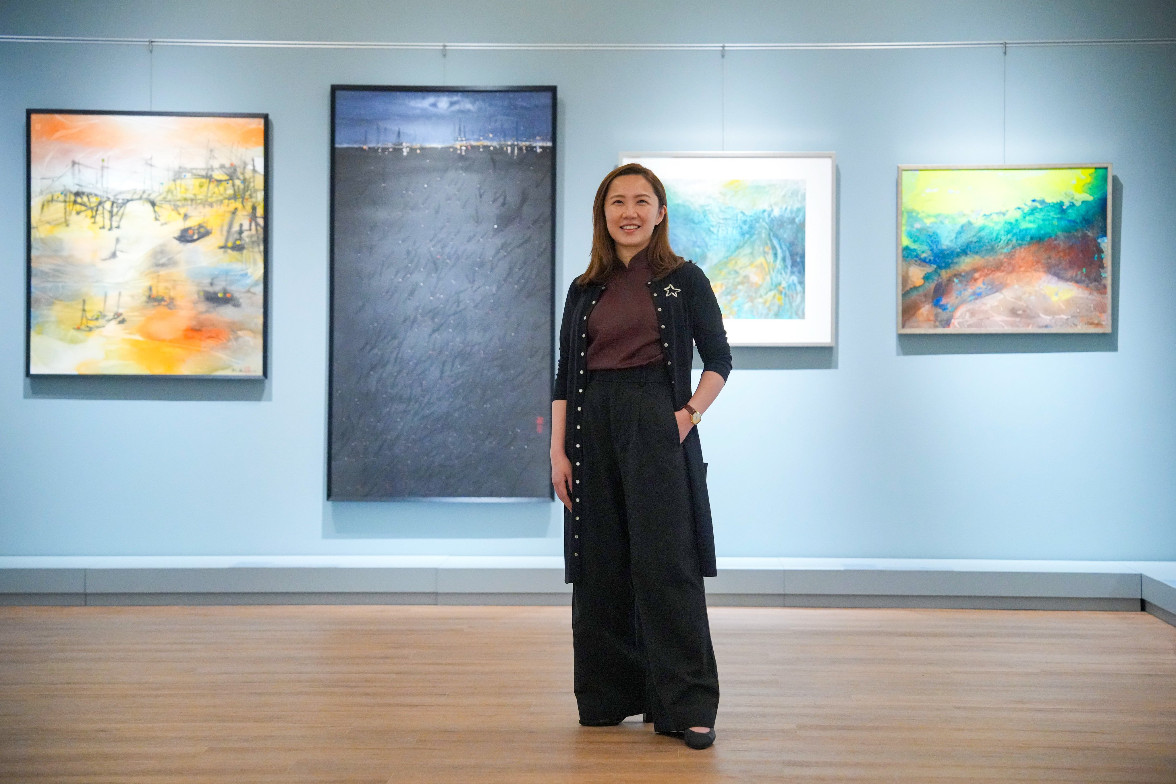 Chloe Sun, founder of Sun Museum, poses with artworks featured in the “Hong Kong Paintings in Sai Yuen Lane” exhibition, which brings together 92 local artists to celebrate the opening of the private museum’s new Sai Ying Pun location. Photo: May Tse