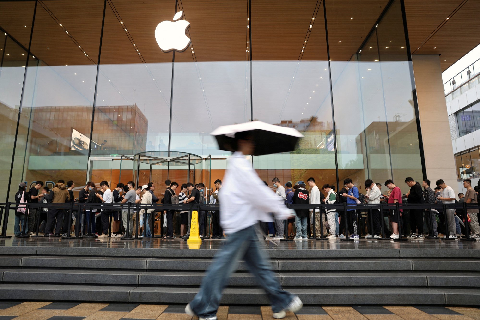 People line up outside an Apple store on a rainy day as the new iPhone 16 series smartphones go on sale in Beijing on September 20. Photo: Reuters