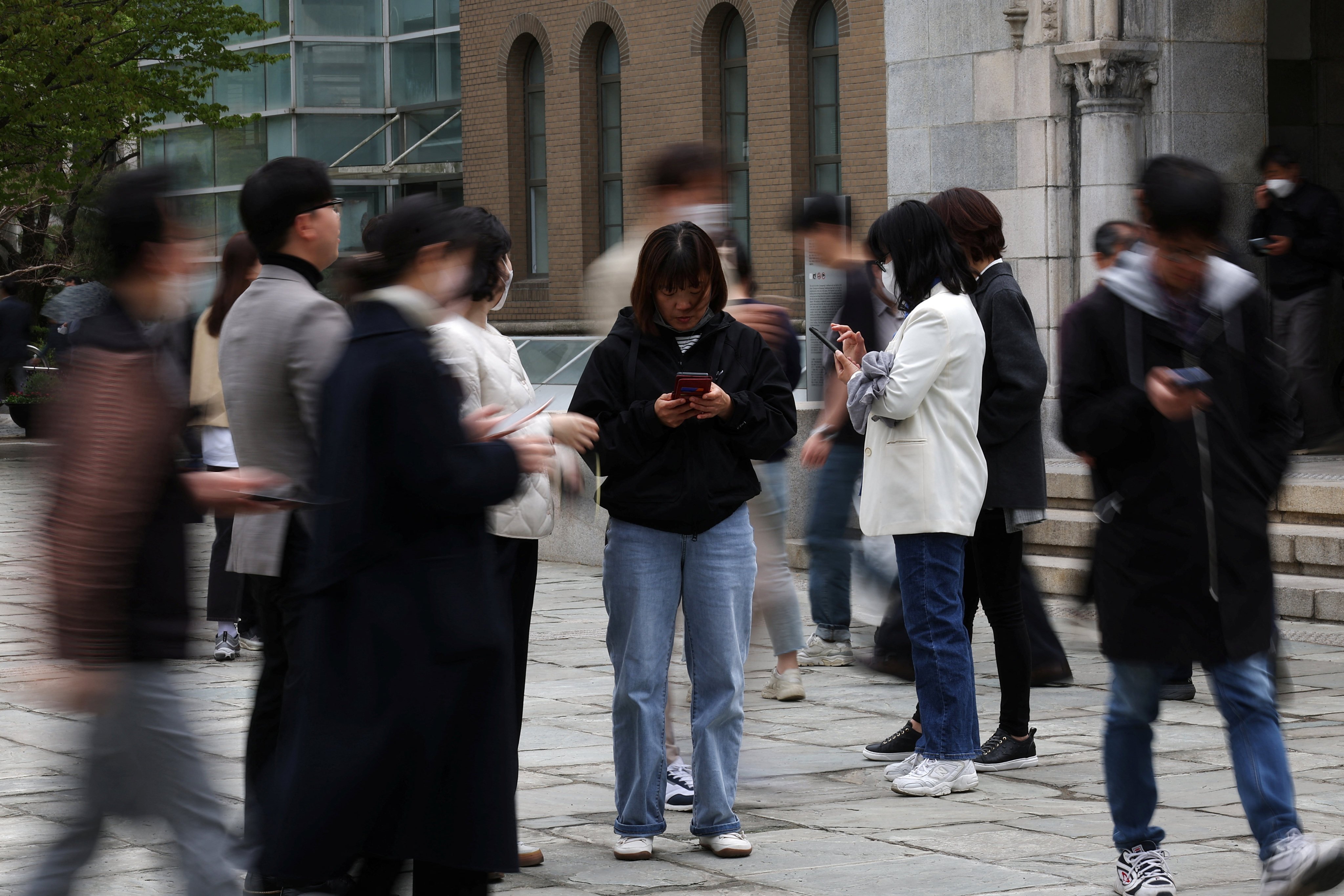 People look at their mobile phones to check the mobile financial app Toss as they gather at Seoul Museum of Art in Seoul on April 13, 2023. Online financial service providers such as Toss have made significant inroads into payments, lending and other areas once dominated by banks. Photo: Reuters