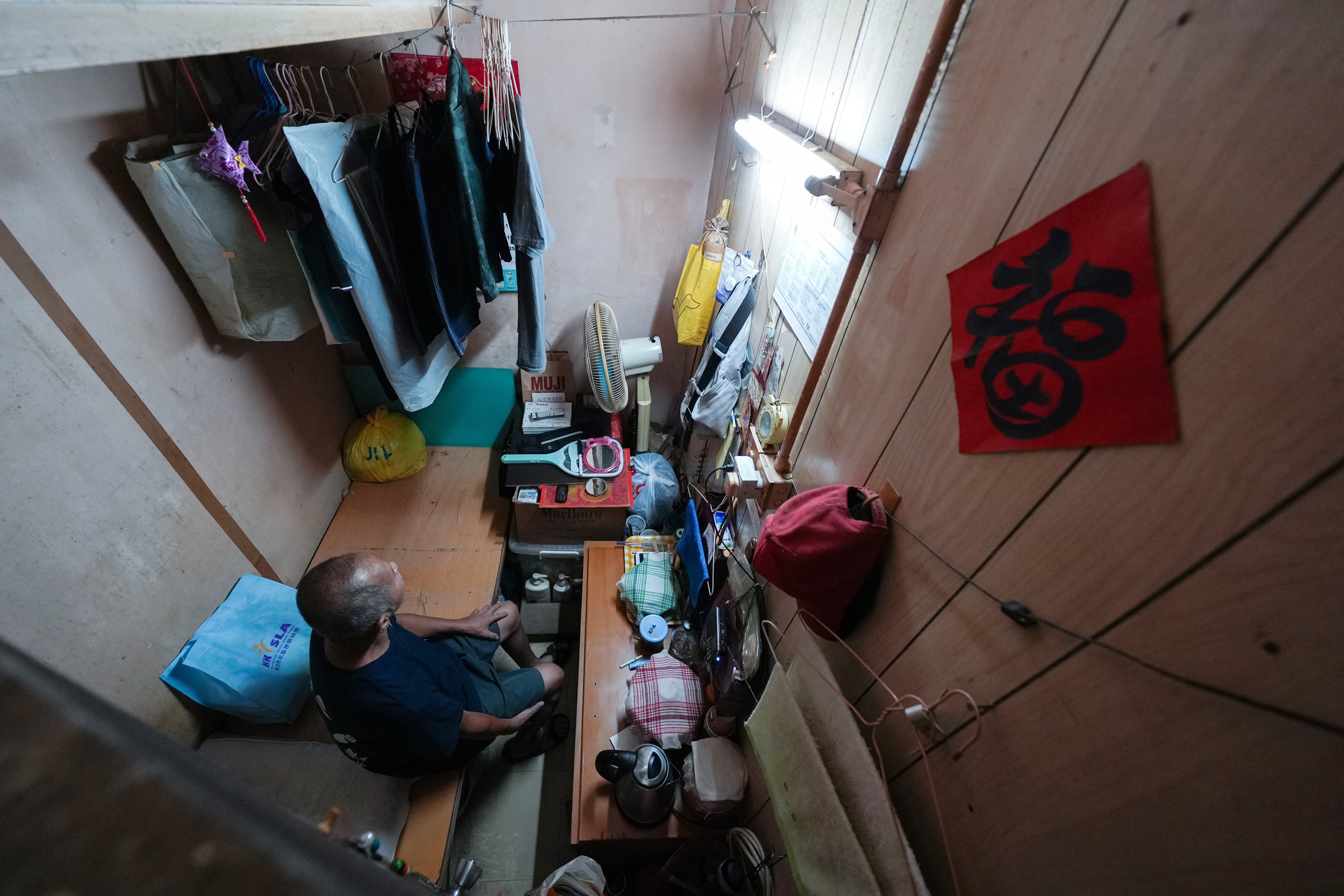 A 66-year-old man surnamed Choy, a semi-retired construction worker, sits in his 40 sq ft subdivided flat with no individual toilet in Sham Shui Po. The flat costs $2,400 per month. Photo: Eugene Lee