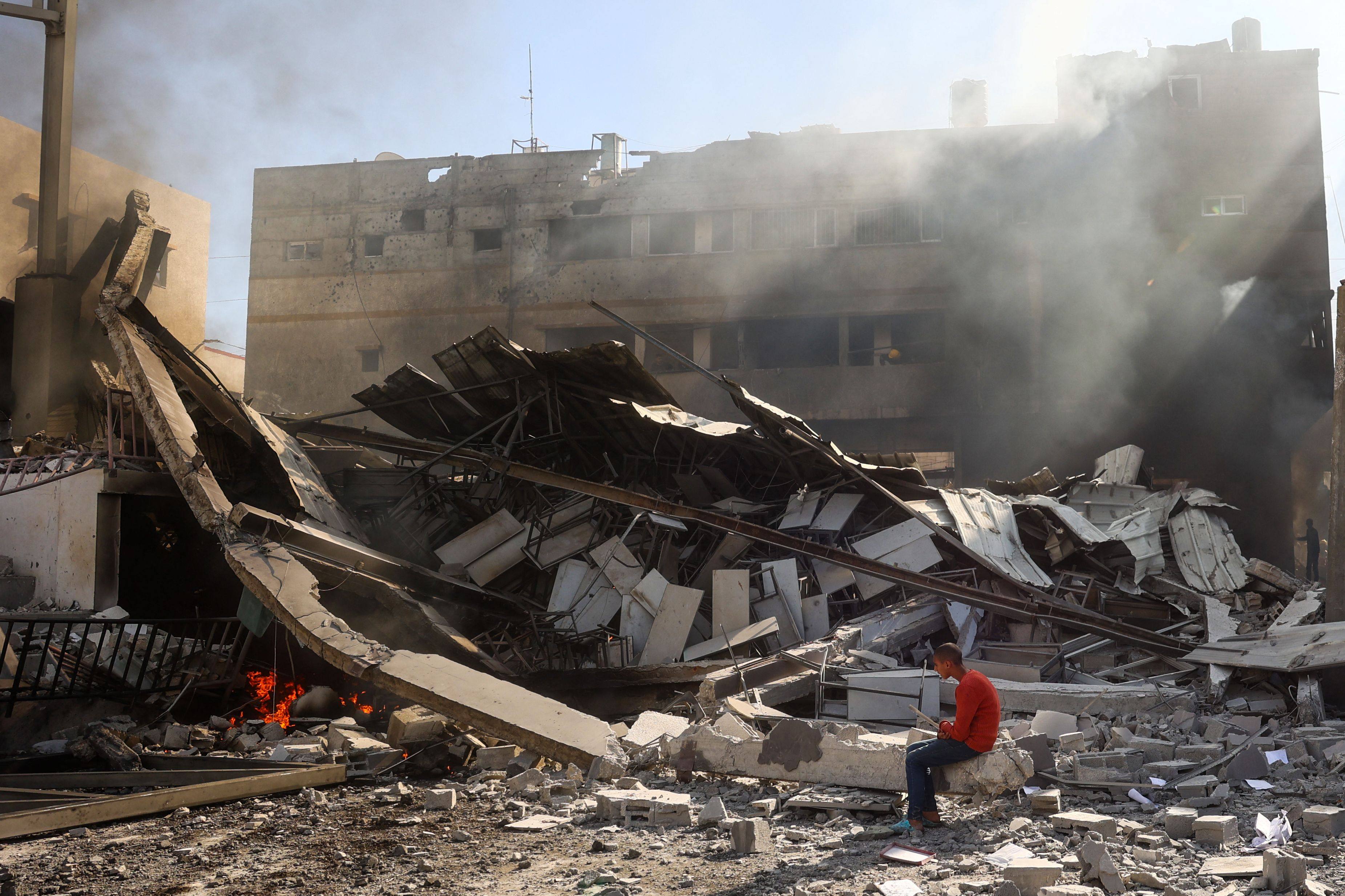 A Palestinian boy sits on the rubble of the destroyed Maghazi Camp Services Club building following an Israeli strike in the Gaza Strip. Photo: AFP