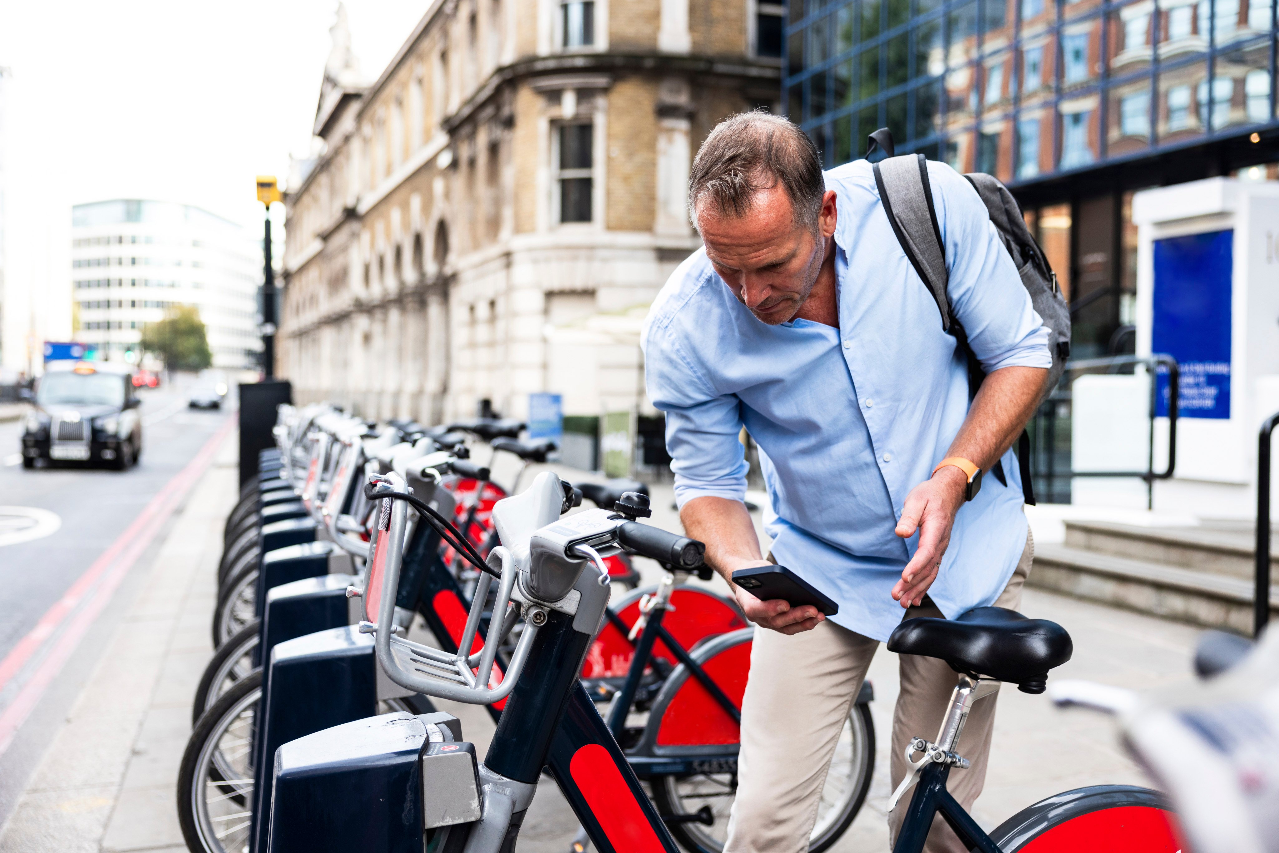 A businessman renting an electric bicycle with a smart phone in London. Photo: Getty Images