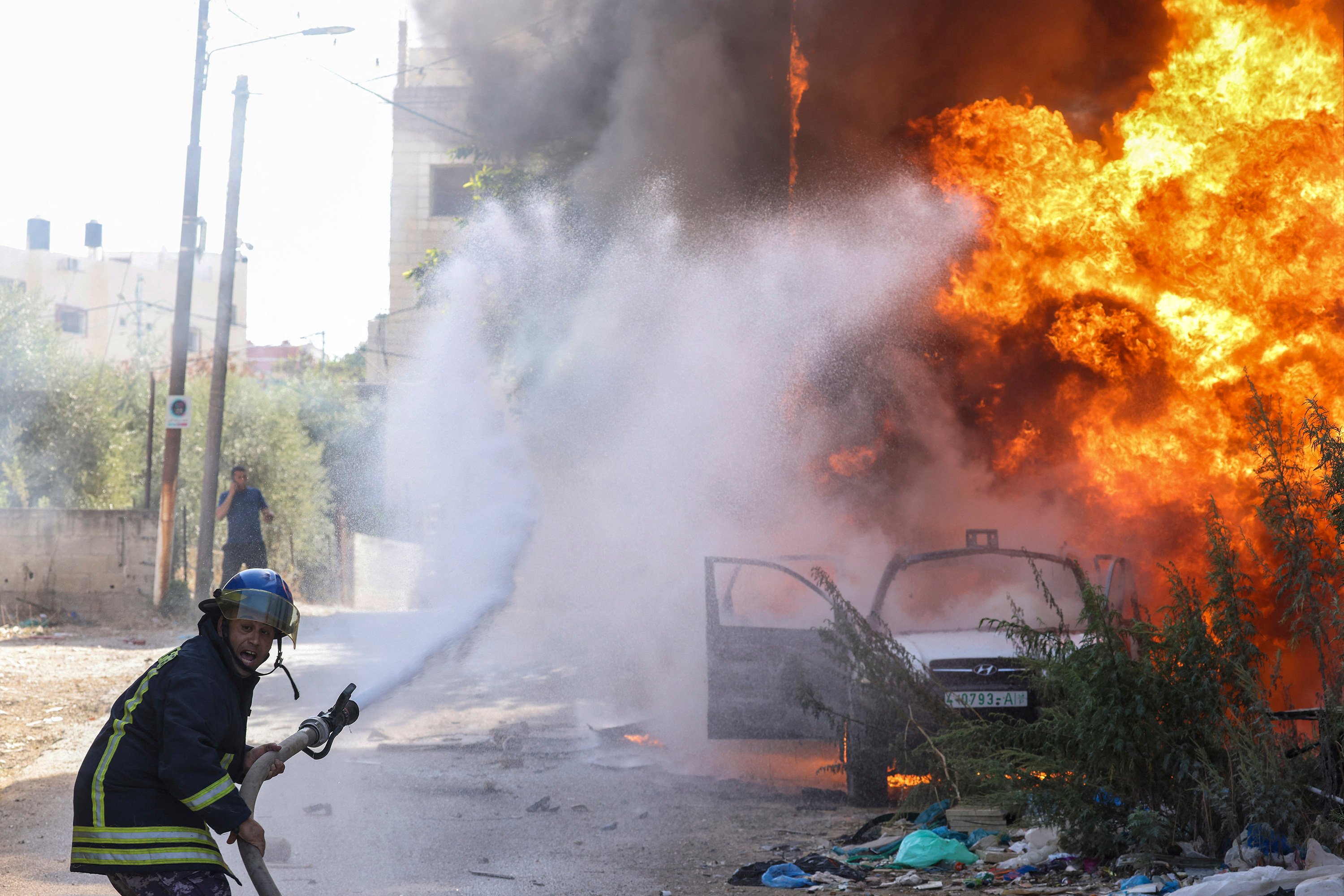 A firefighter douses the flames engulfing a car following an Israeli raid in Tulkarem in the West Bank. Photo: AFP