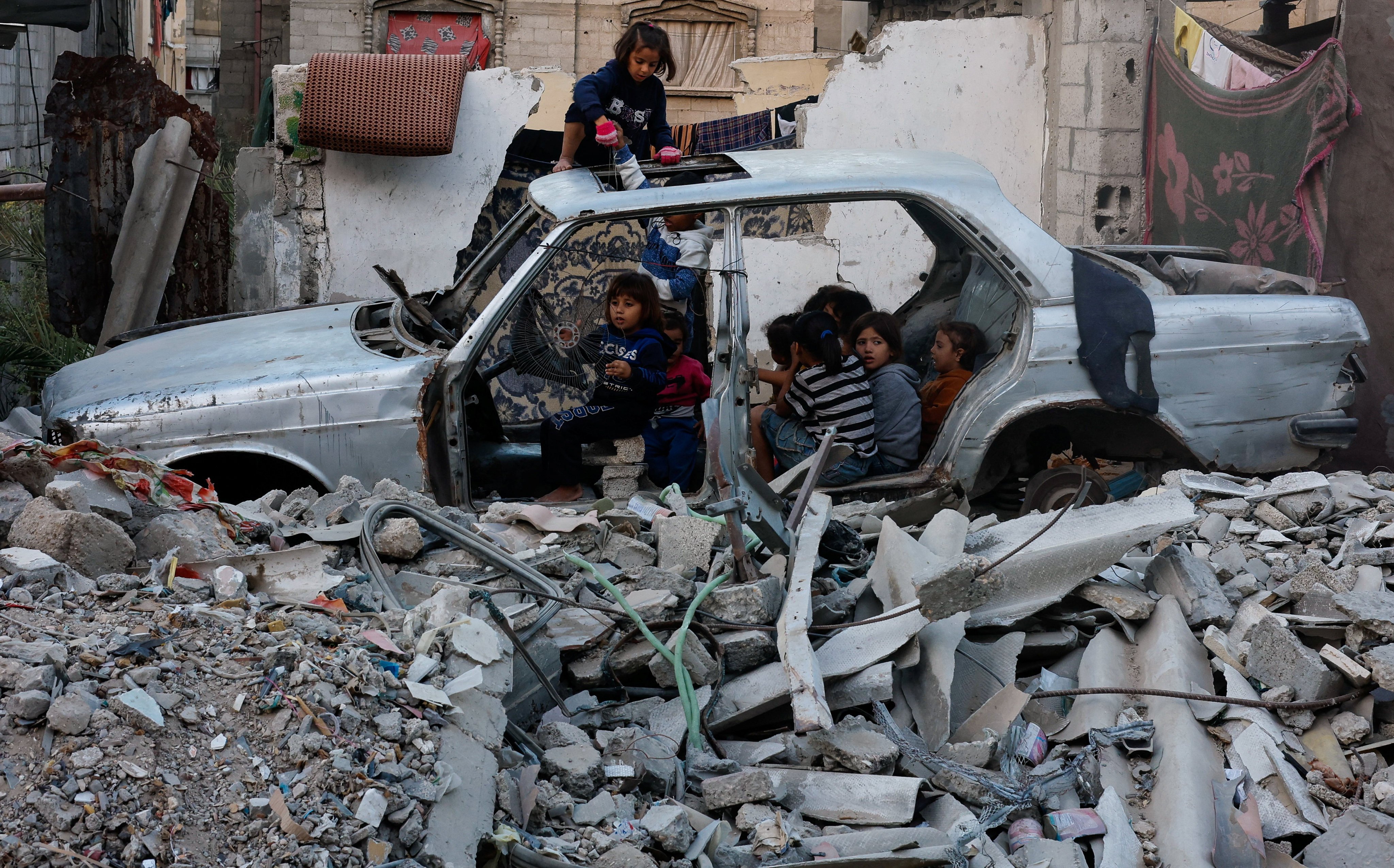 Palestinian children gather at a destroyed vehicle in Khan Younis, in the southern Gaza Strip. Photo: Reuters