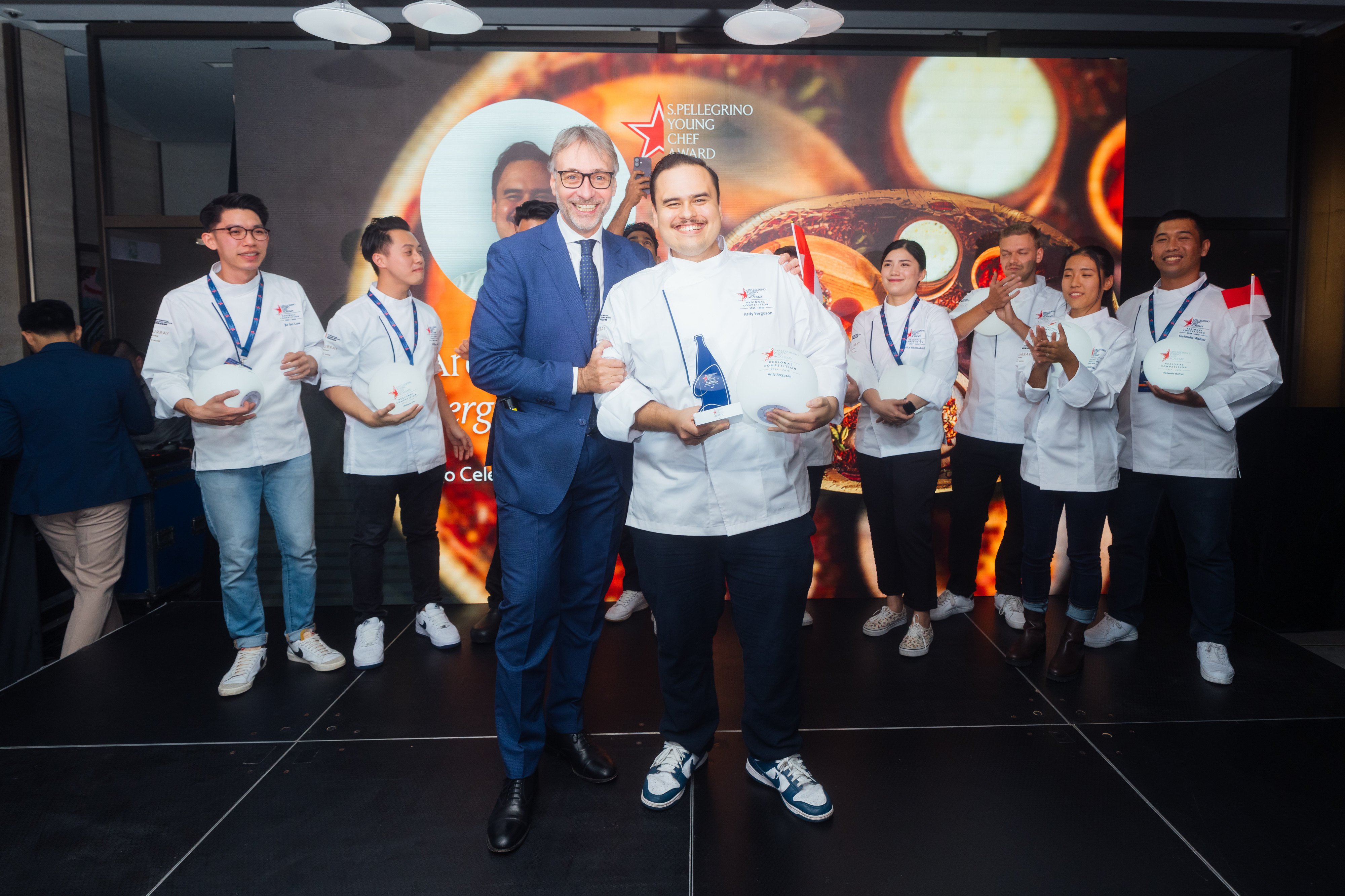 Ardy Ferguson (centre, with award), winner of the S.Pellegrino Young Chef Academy Competition 2024-25 Asia Regional Final, poses with San Pellegrino’s Roberto Caroni and other finalists in Hong Kong on October 28, 2024. Photo: S.Pellegrino Young Chef Academy