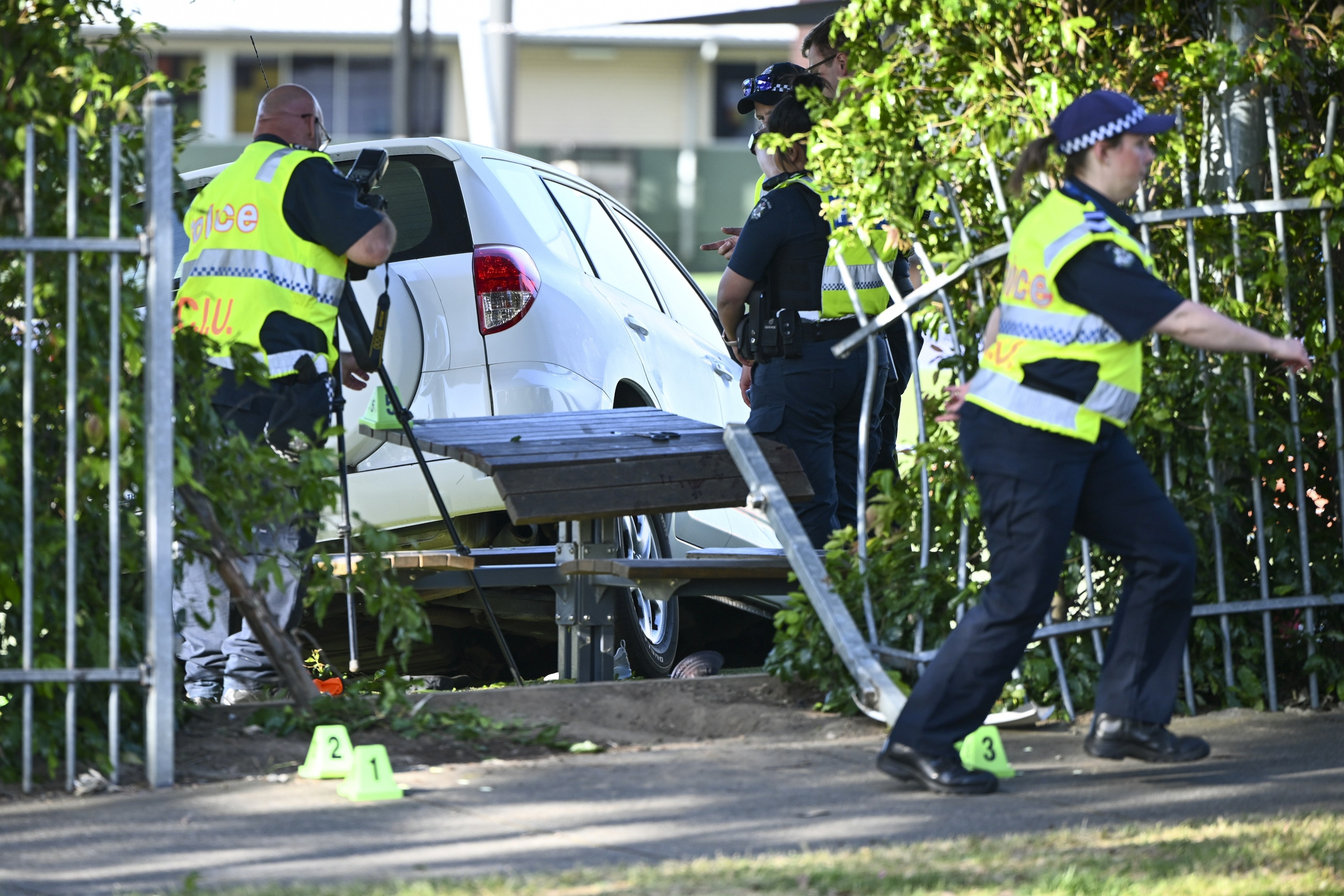 Police officers attend to the scene of an accident where a car crashed through a school fence in Melbourne, Australia, on Tuesday. Photo: AAP Image via AP