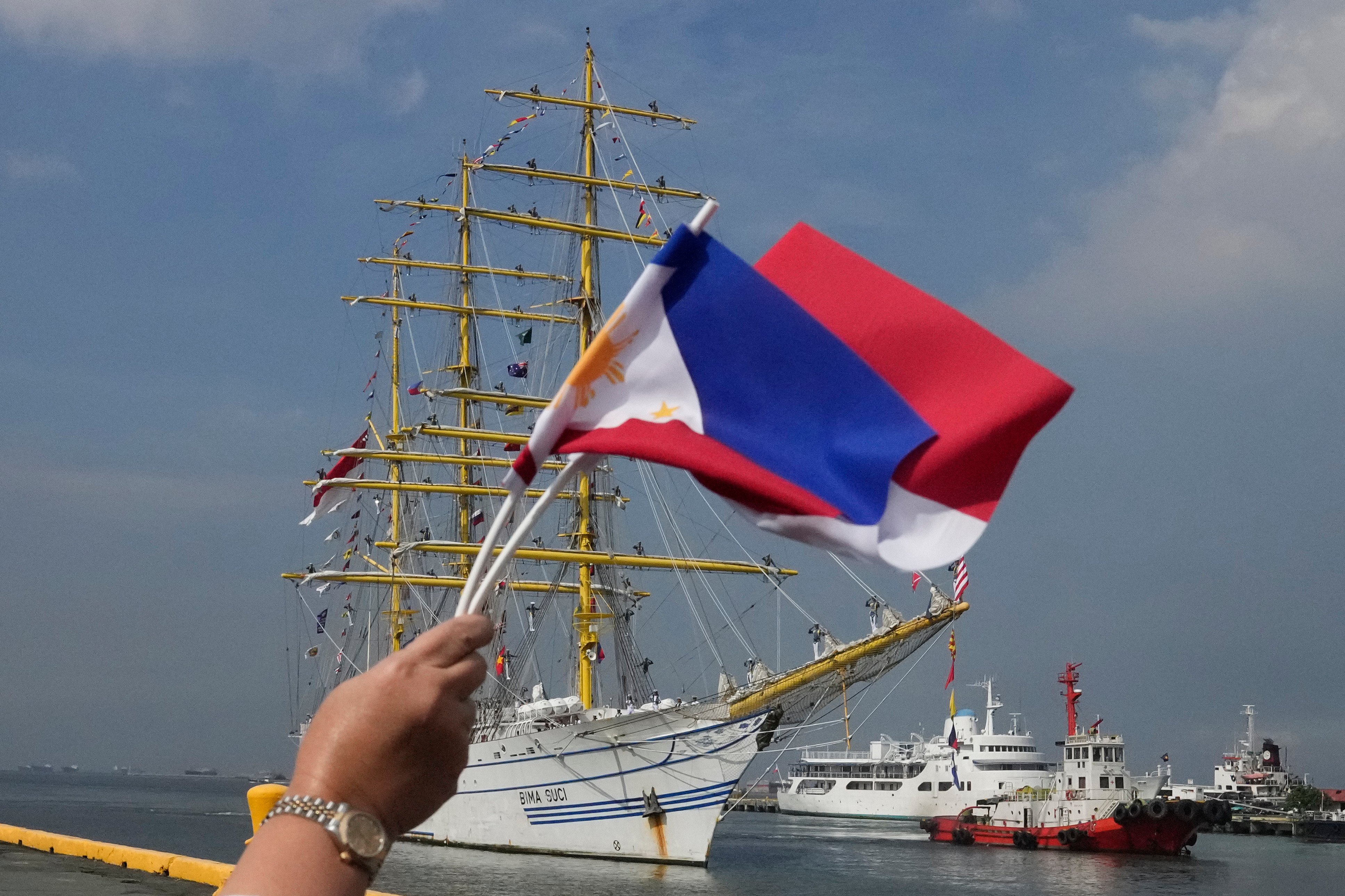 A woman waves the Philippine and Indonesian flags as an Indonesian Navy training ship prepares to dock for a goodwill visit in Manila on October 15. Photo: AP