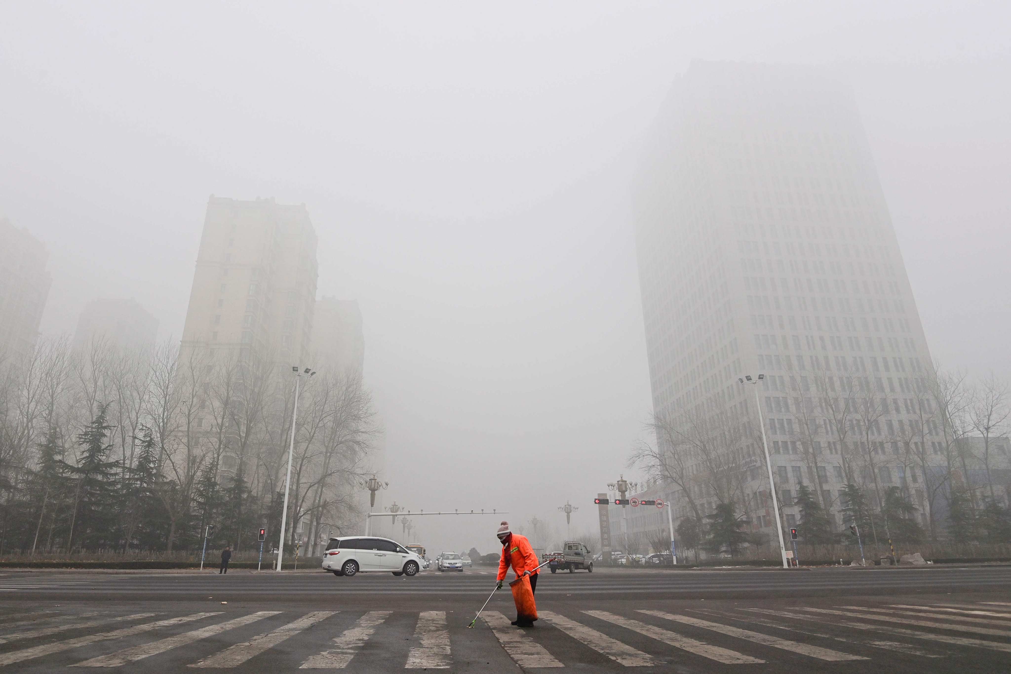 A street cleaner works as fog and air pollution shroud buildings in Qingzhou, in China’s eatern Shandong province, on December 28, 2023. Photo: AFP