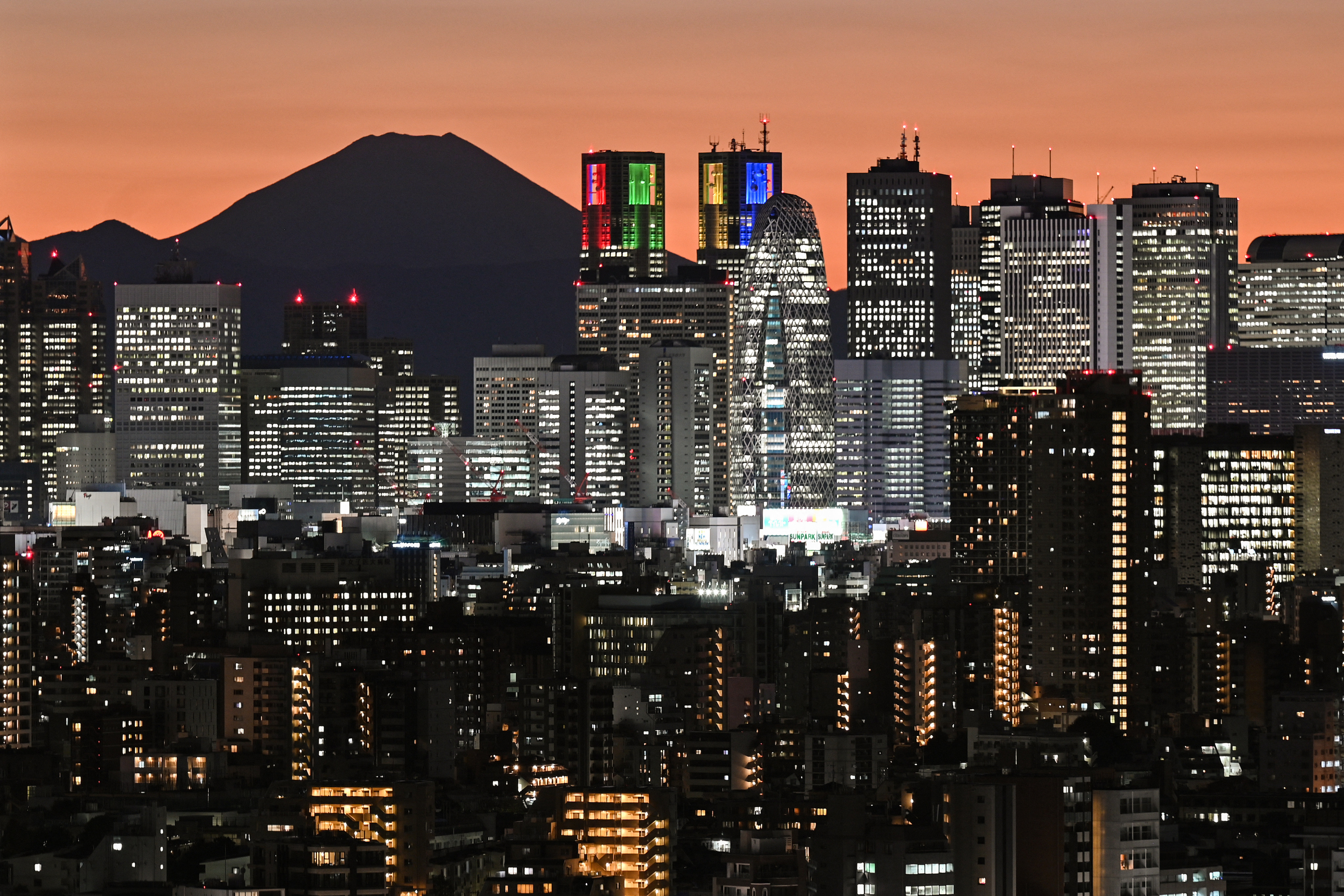 Mount Fuji, Japan’s highest mountain, is seen silhouetted behind the high-rise buildings of downtown Tokyo during sunset. Photo: AFP