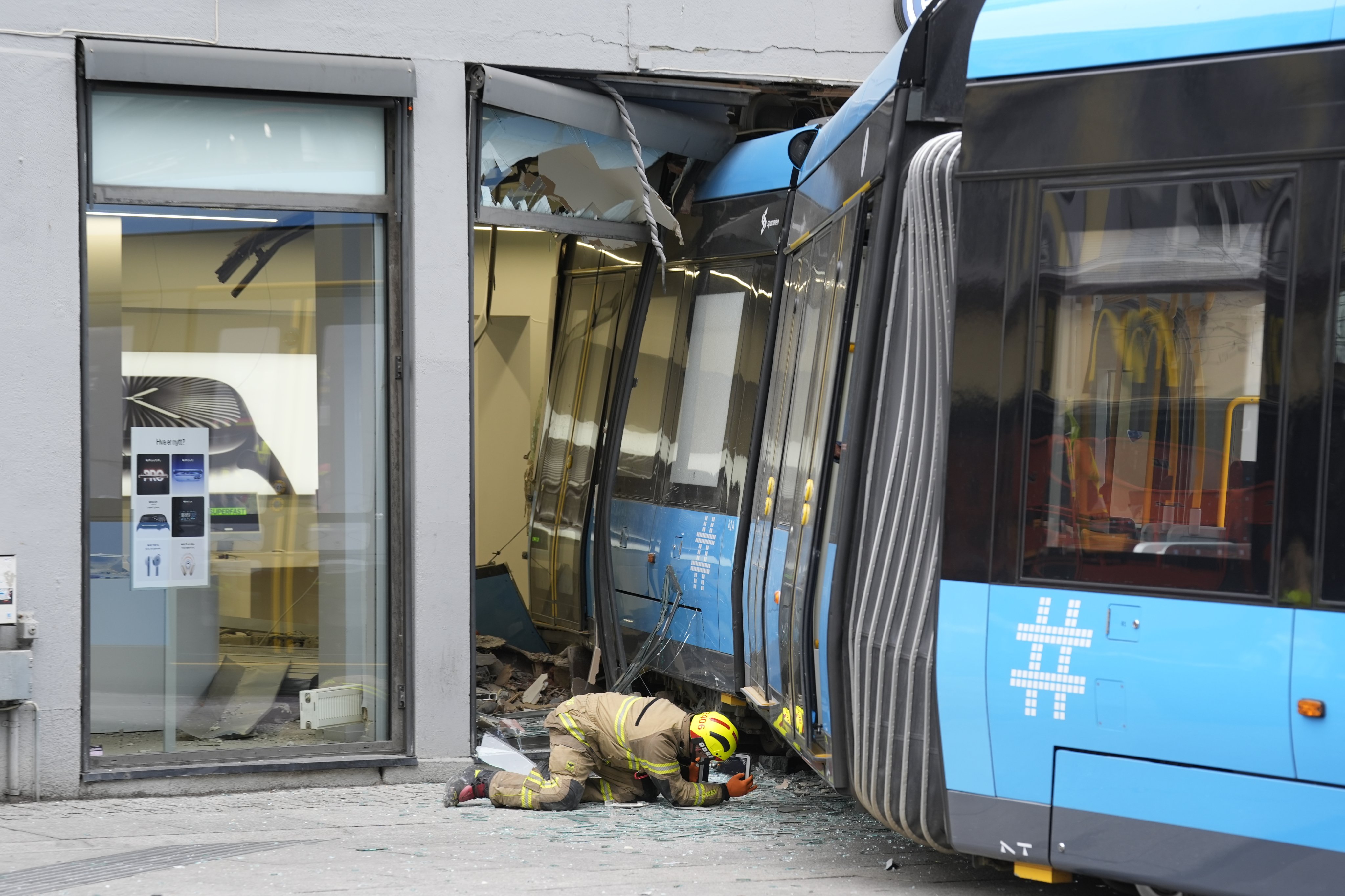 A rescuer works at the scene of the tram derailment that collided with an Apple product store located on Storgata, one of the busiest streets in Oslo. Photo: EPA-EFE