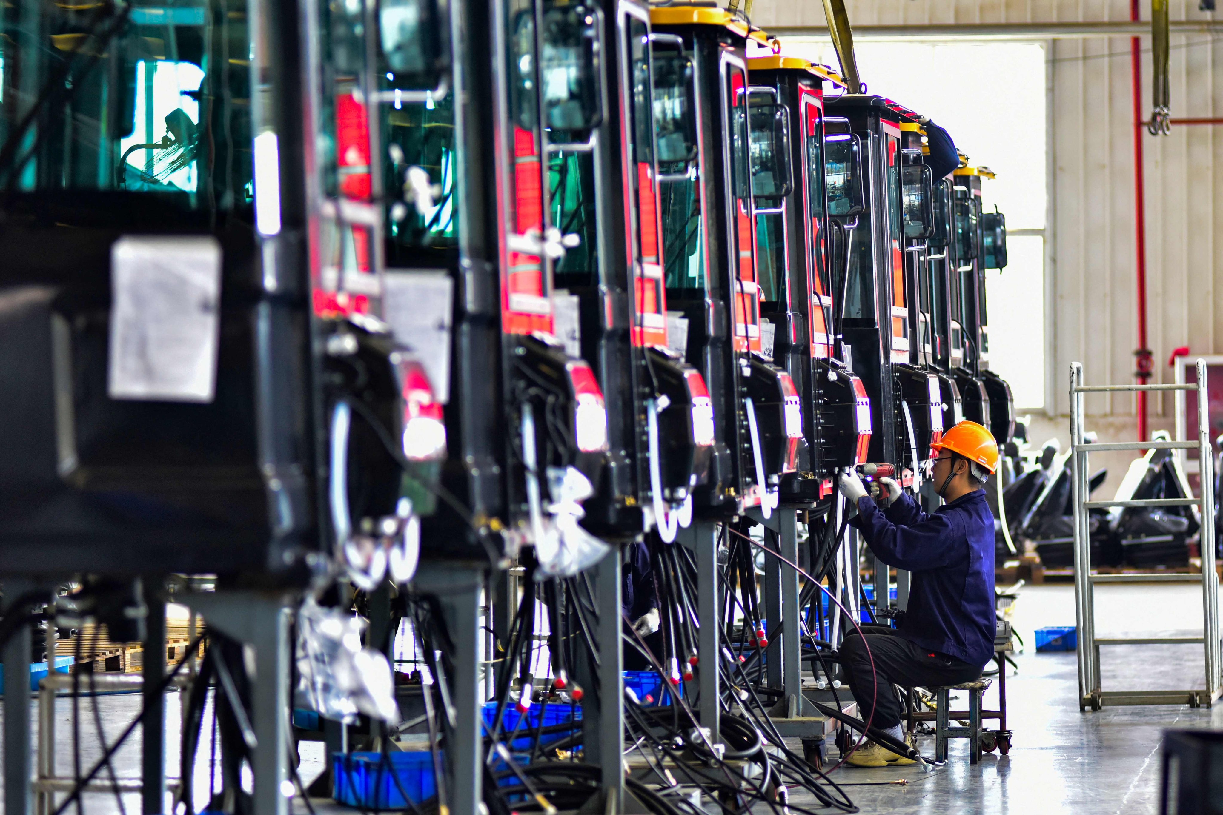 Workers build cabs for excavators at a factory in Qingzhou, in China’s eastern Shandong province. Photo: AFP