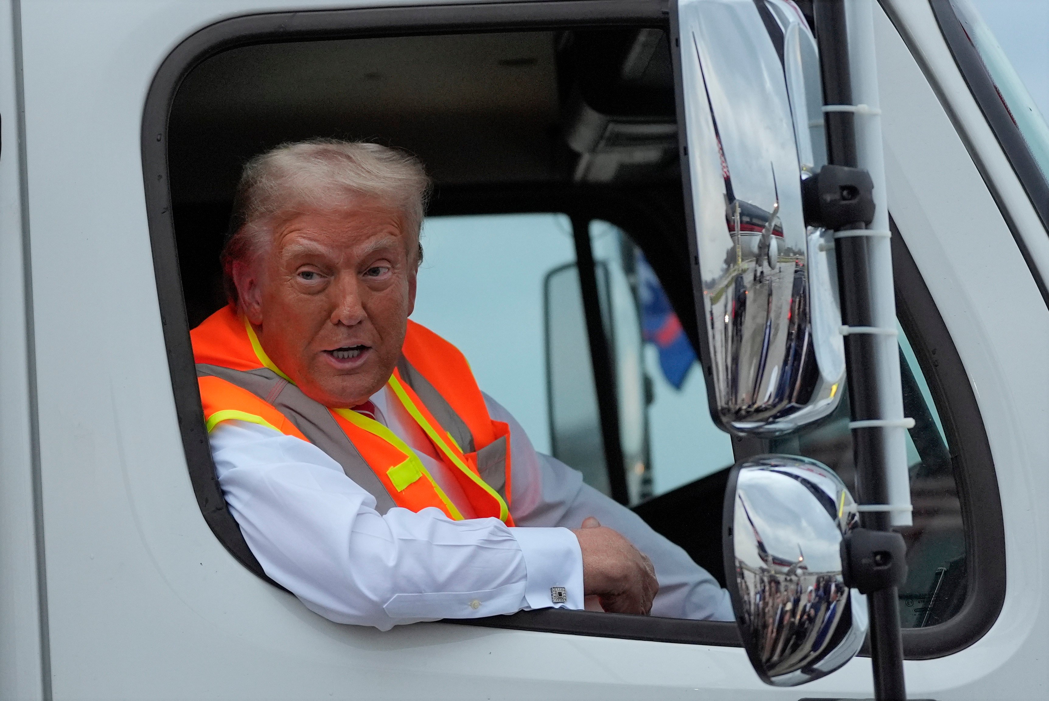 Donald Trump talks to reporters as he sits in a garbage truck. Photo: AP