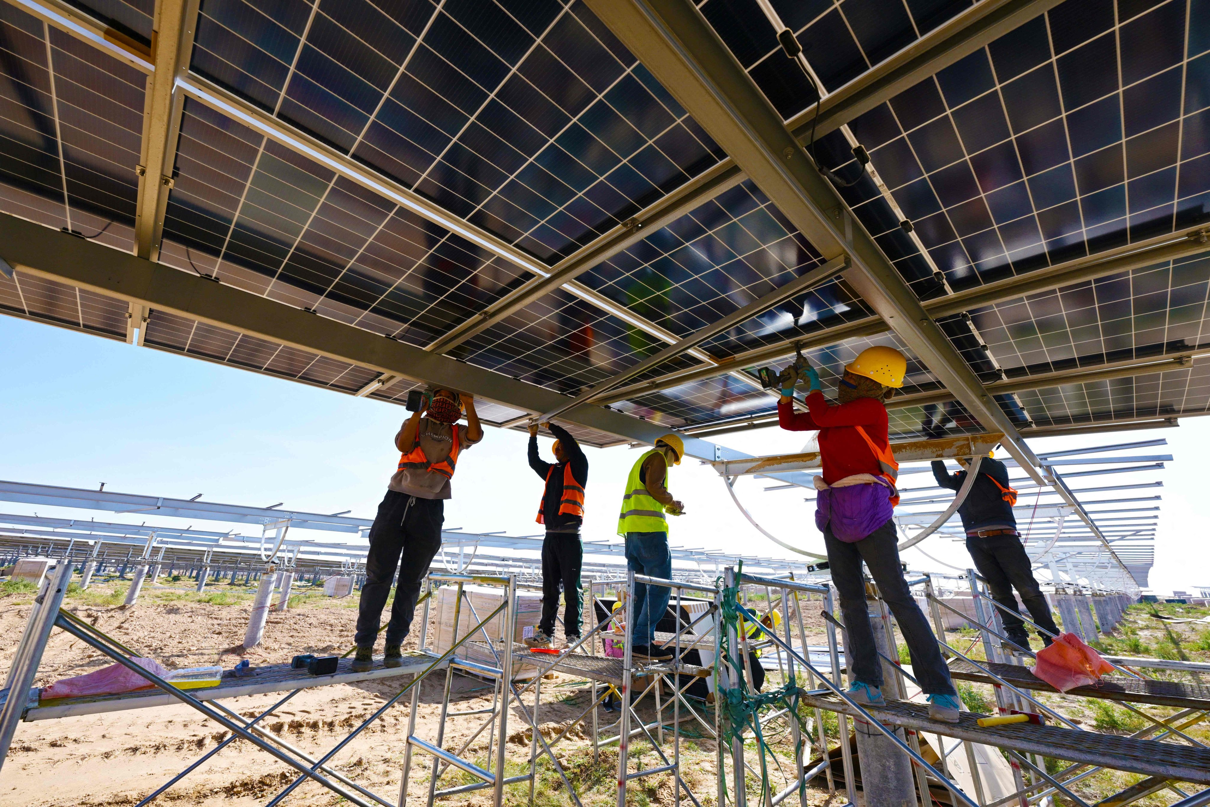 Workers installed solar panels at a photovoltaic base in Lingwu, China. Photo: AFP 