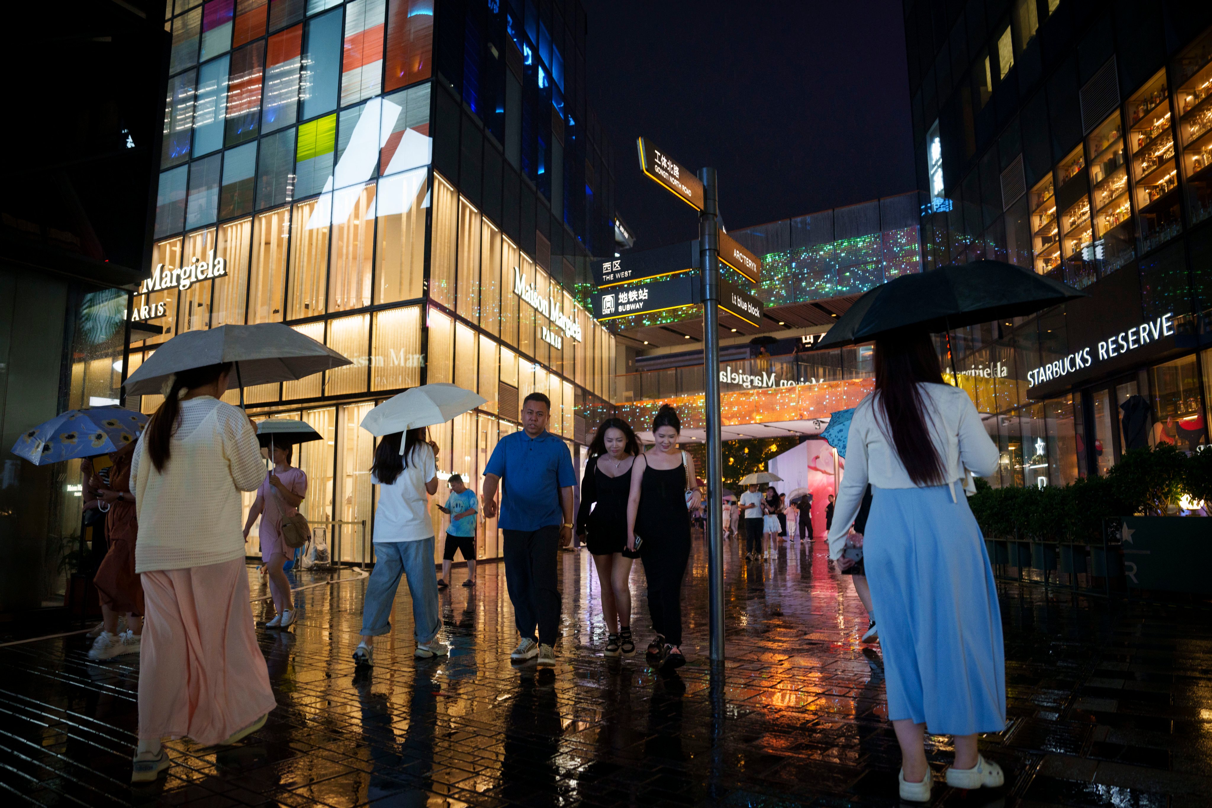 Pedestrians in the rain at Taikoo Li Sanlitun in Beijing on July 30, 2024. Photo: AP