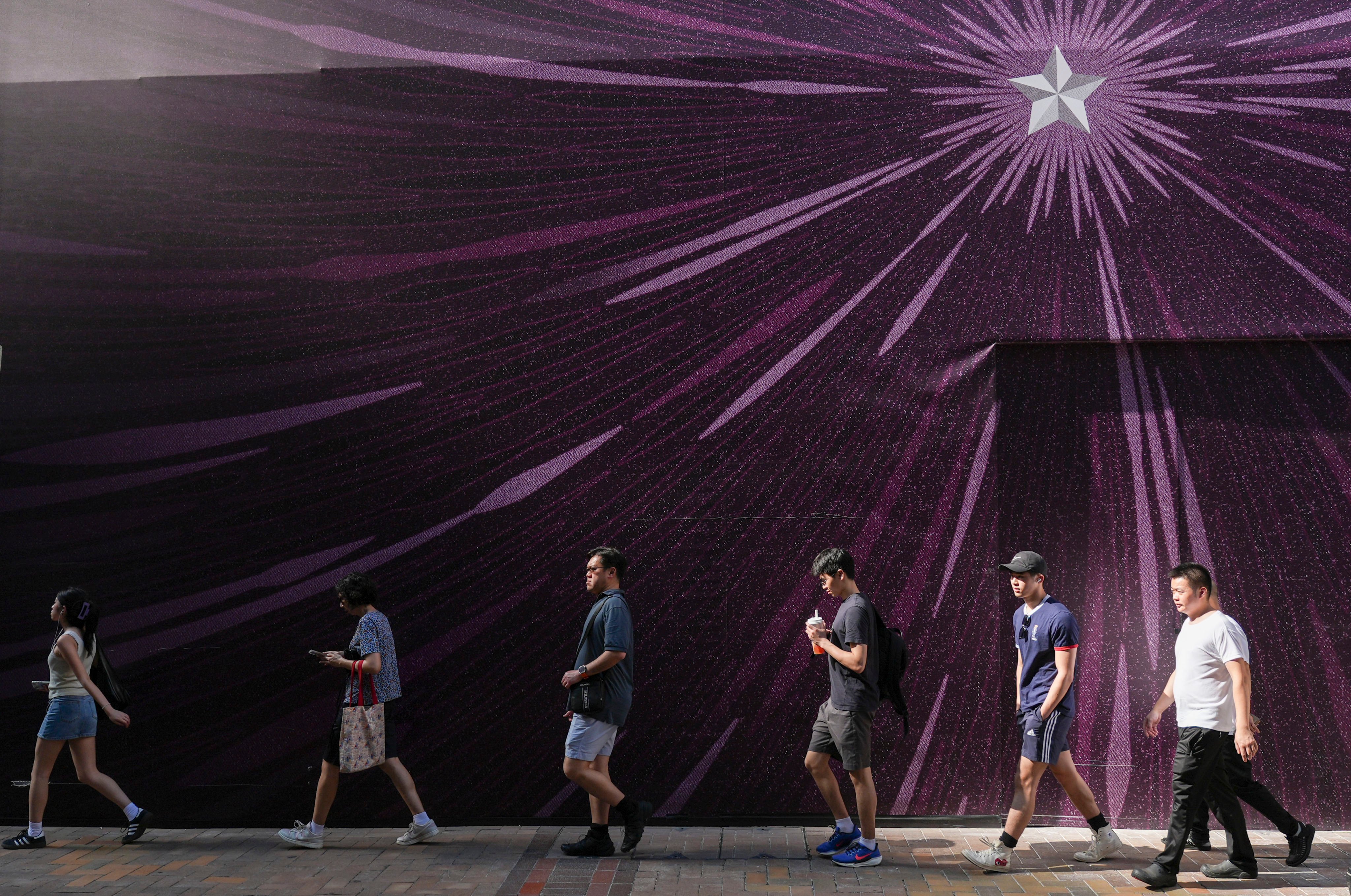 Pedestrians walk past a purple advertisement hoarding in Causeway Bay. Photo: Eugene Lee