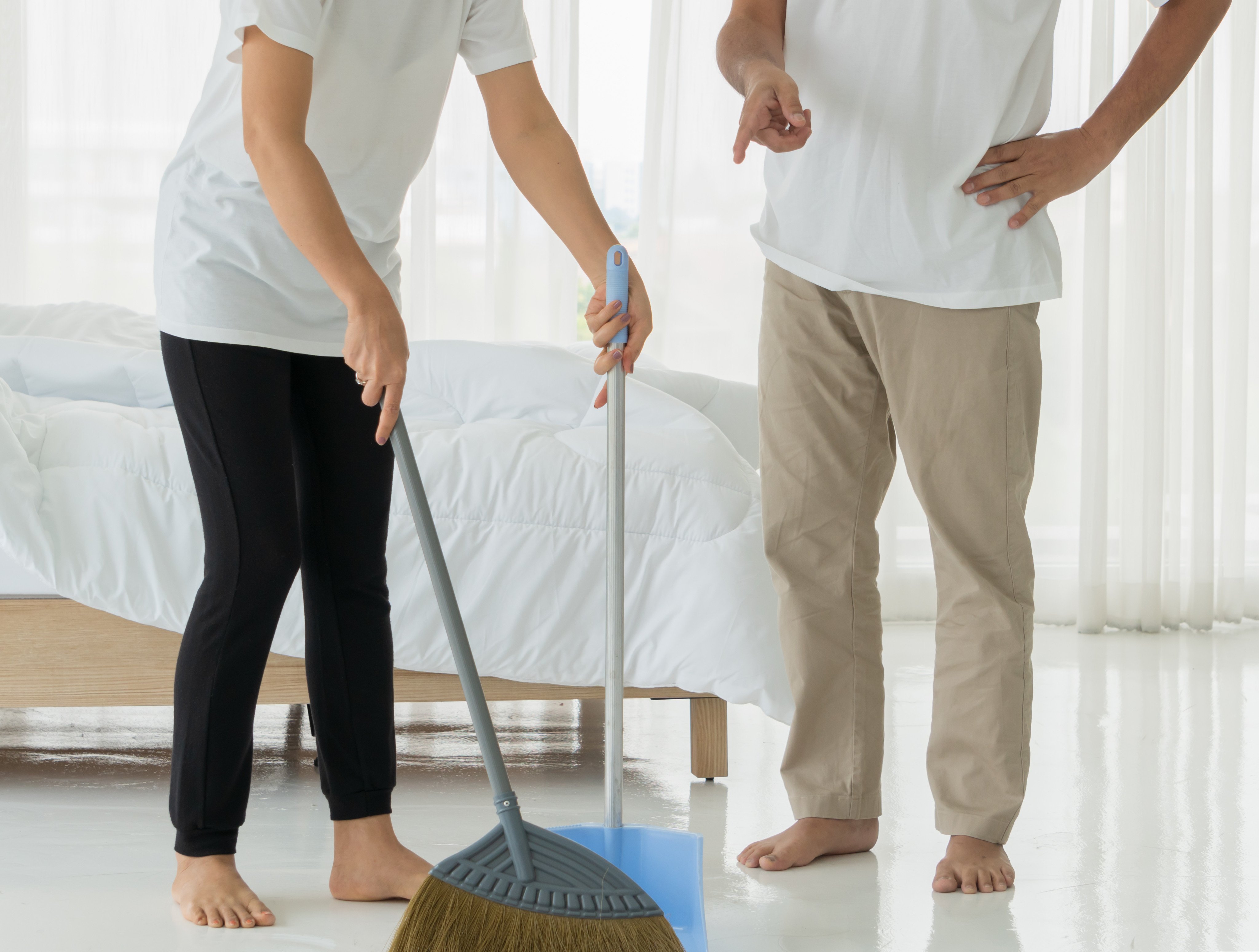 A woman cleaning a room with a man standing next to her. Photo: Shutterstock