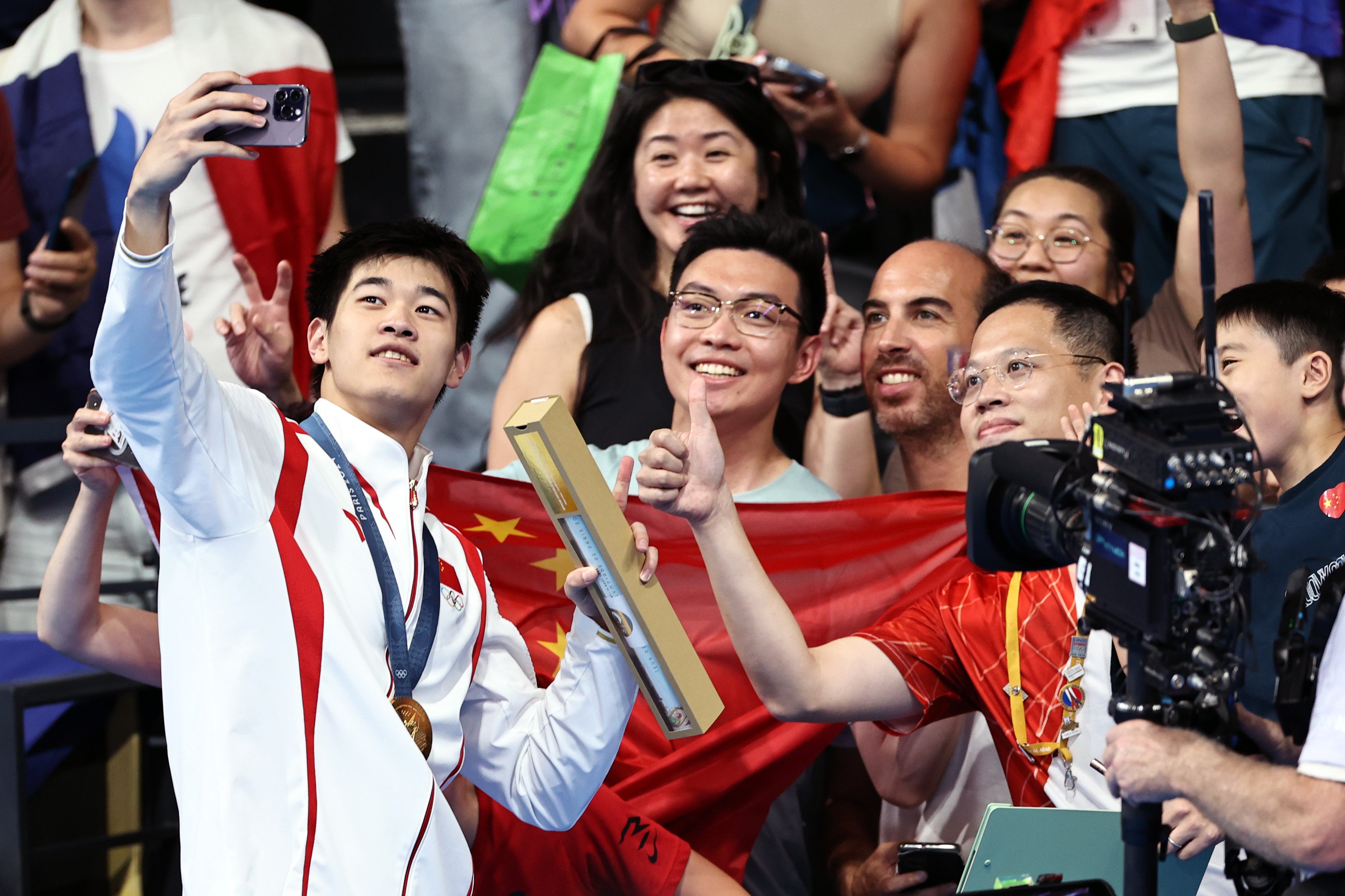 Olympic gold medallist Pan Zhanle takes selfies with spectators after the victory ceremony for the 100m freestyle at the Paris Games in July. Photo: Xinhua