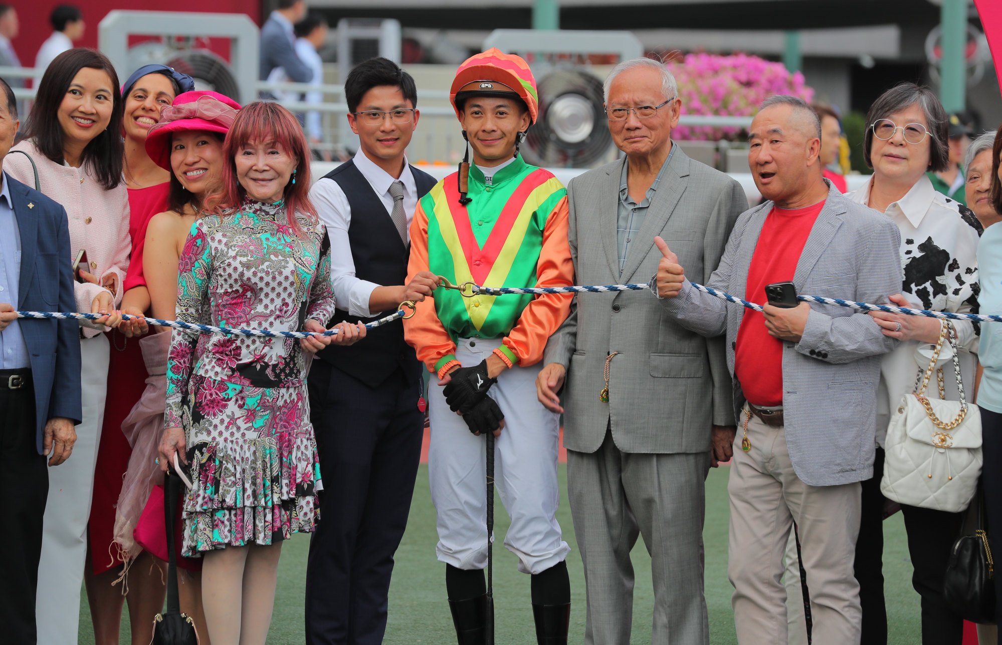 Jockey Derek Leung celebrates with connections while trainer Jimmy Ting rushes to hospital.