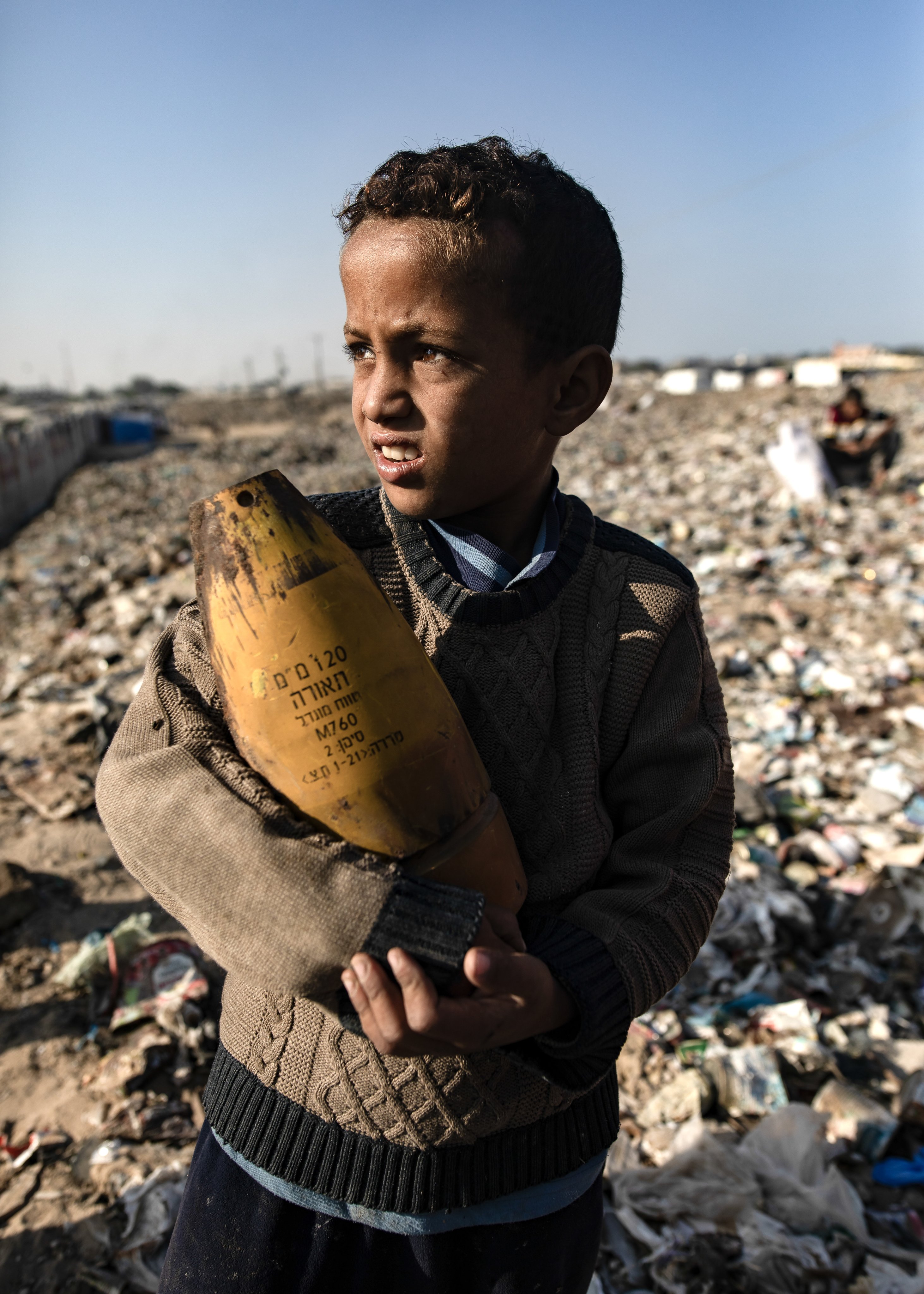 A Palestinian boy holds an Israeli artillery shell, found while sorting through rubbish amid a shortage of cooking gas and fuel, at the Khan Younis refugee camp in the southern Gaza Strip on Monday. Photo: EPA-EFE