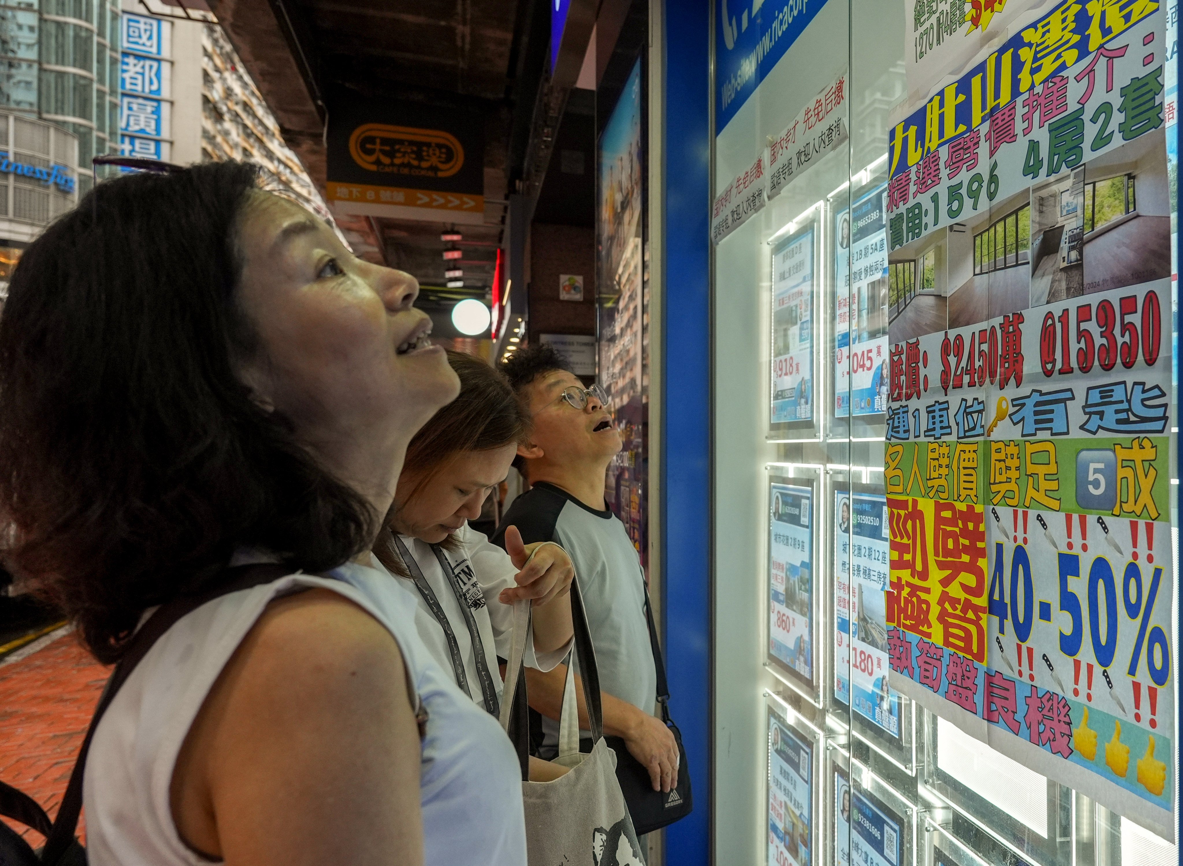 A poster in the window of a real estate agency in Fortress Hill, Hong Kong, shows deeply discounted house prices, on July 29. Photo: Eugene Lee