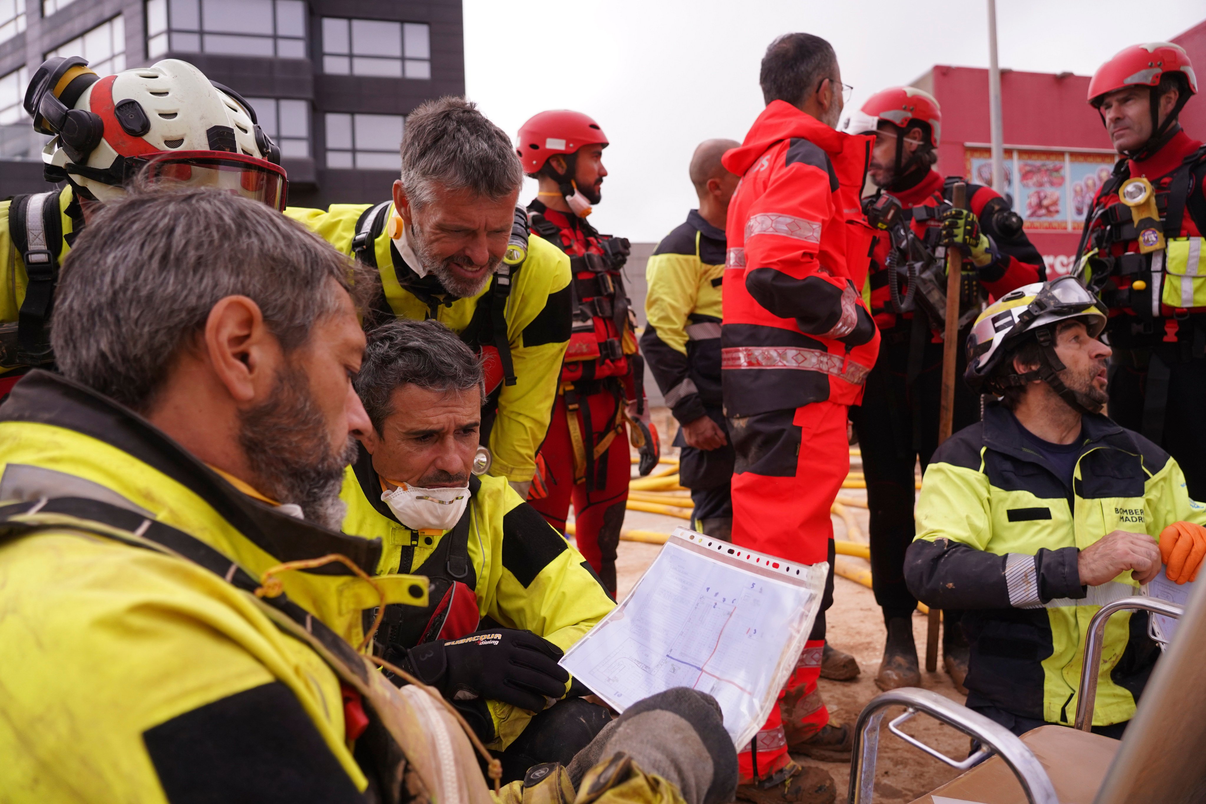 Rescue workers look at a plan of a Valencia shopping centre on Monday as the search for bodies continues after devastating floods. Photo: AP