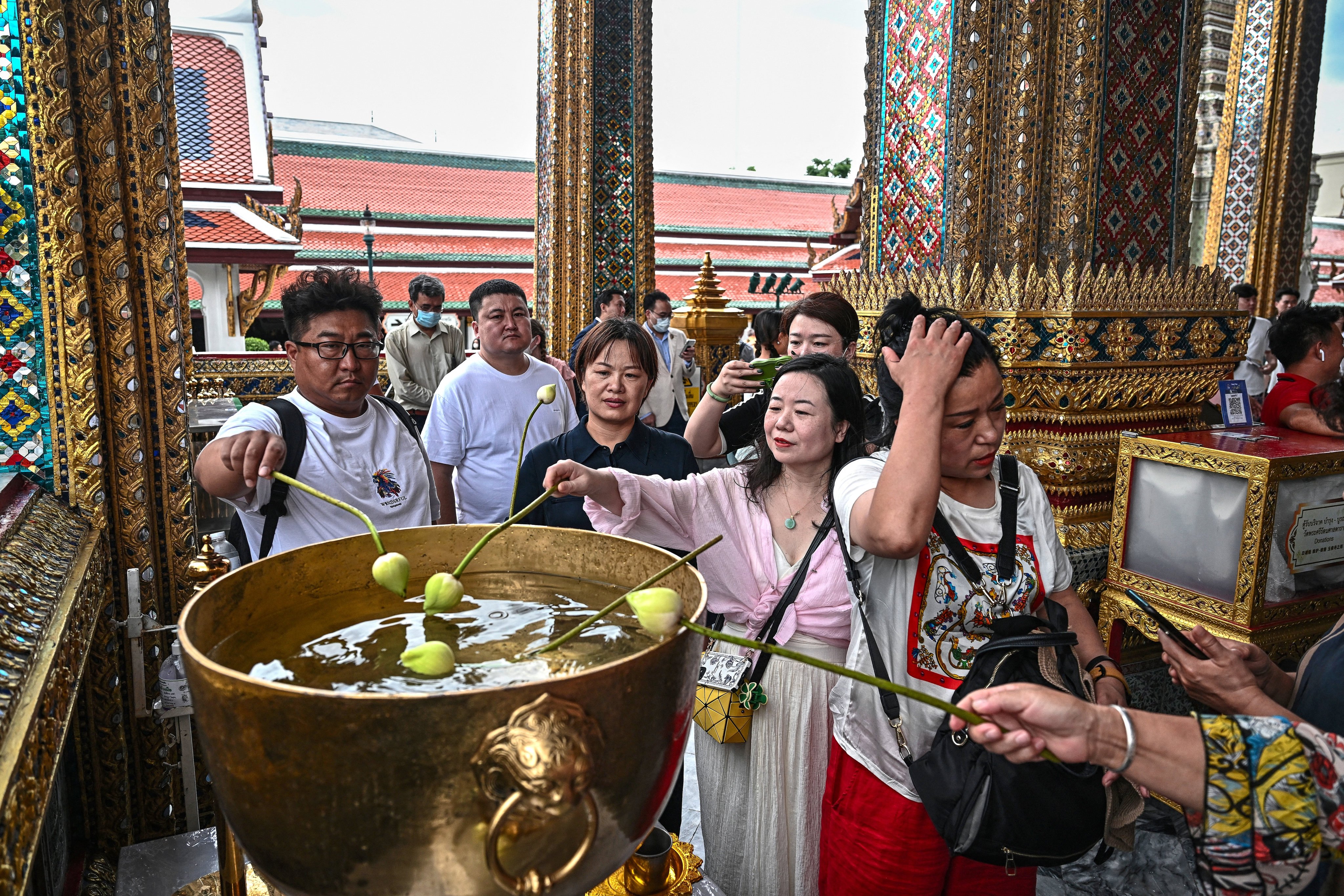 Chinese tourists dip lotus bulbs in a water bowl at the Grand Palace in Bangkok in September last year. Photo: AFP