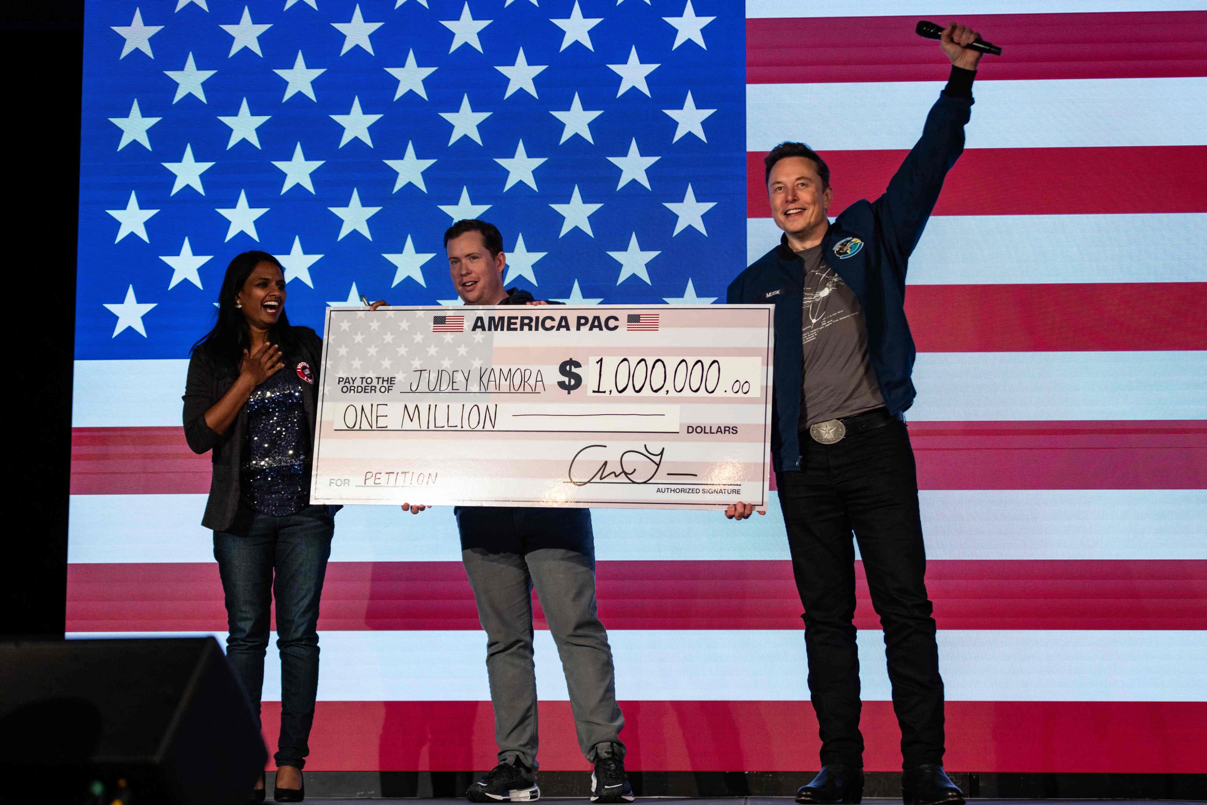 Elon Musk presents a US$1 million cheque to a voter during an America PAC town hall on October 26. Photo: AFP