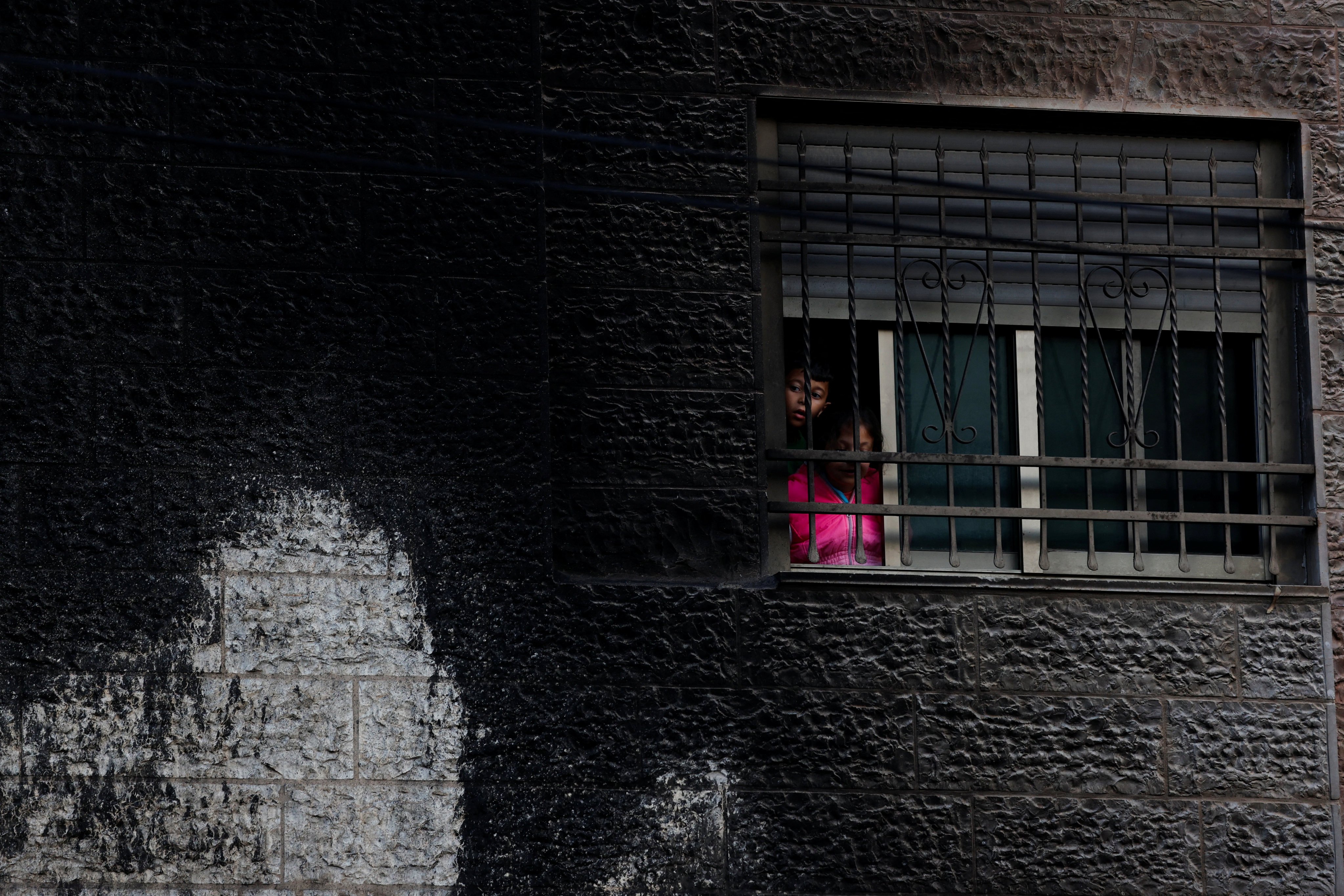 Palestinians look through a window after an Israeli settlers attack in Al-Bireh city, in the Israeli-occupied West Bank. Photo: Reuters