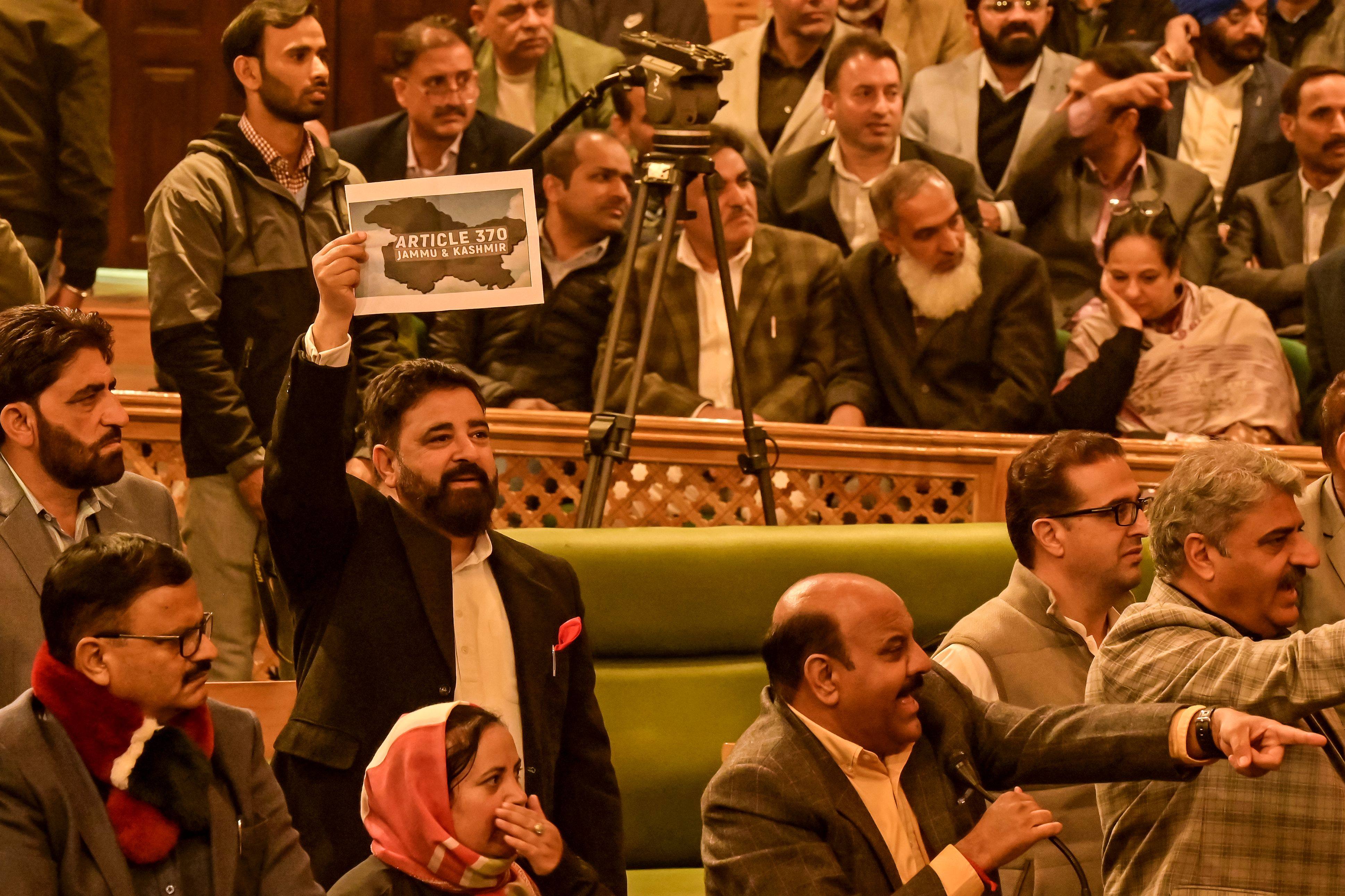 A member of Jammu and Kashmir’s legislative assembly holds a poster in support of a resolution to restore the state’s special status during a session in Srinagar on November 6. Photo: AFP