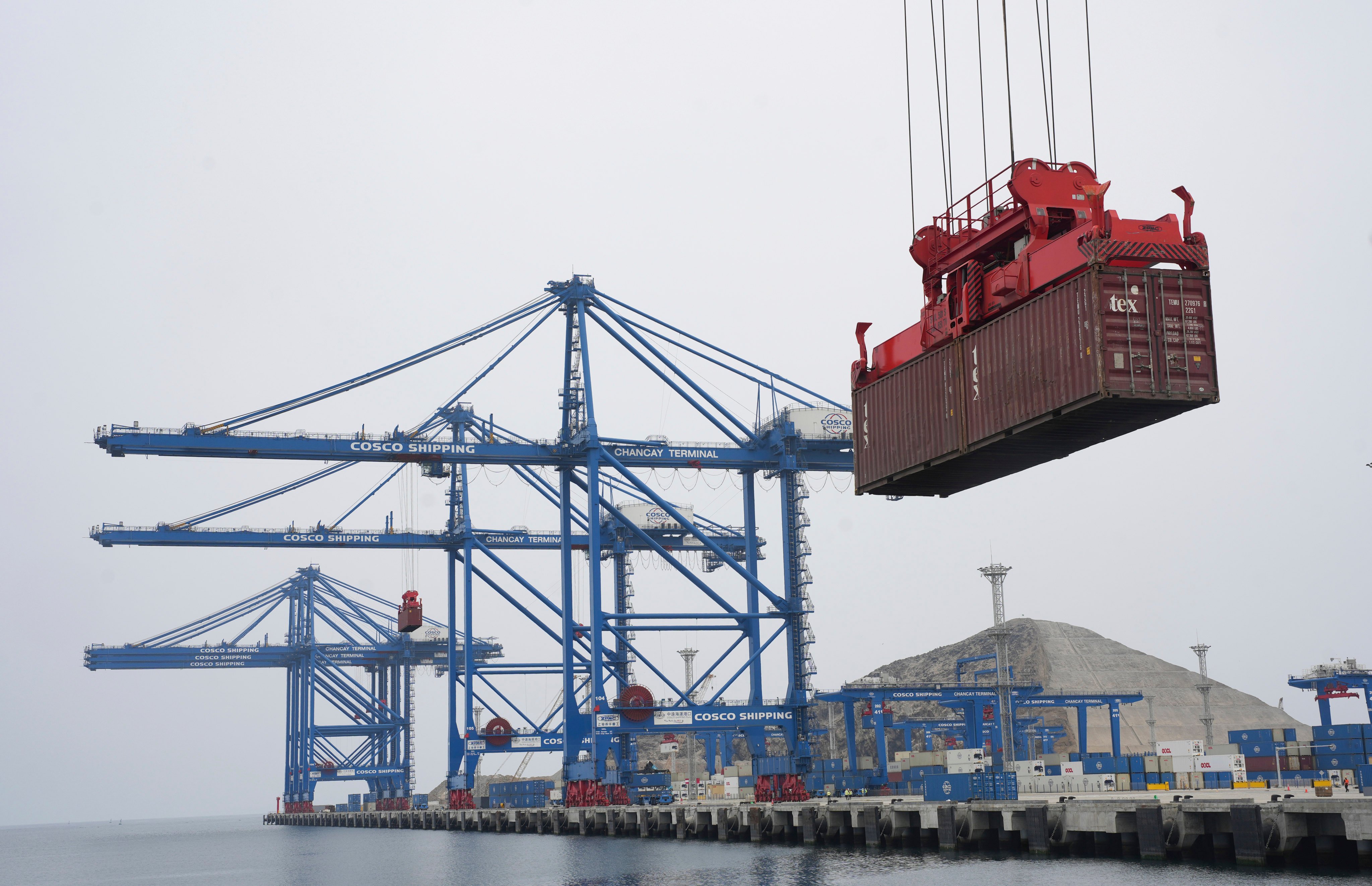 A container is lifted by a crane backdropped by the construction of the Chinese-funded port in Chancay, Peru. Photo: AP