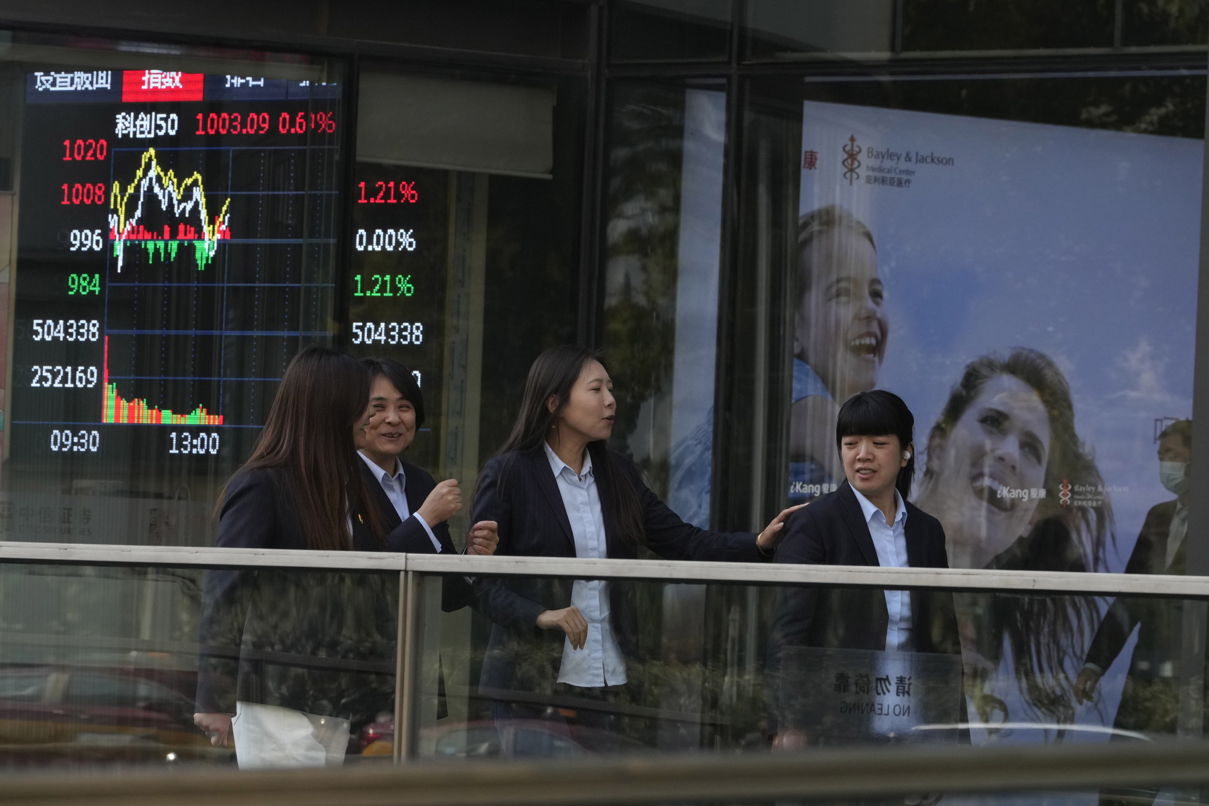 People pass by a display board showing Chinese stock market movements on November 6, in Beijing, during the US presidential election. Photo: AP