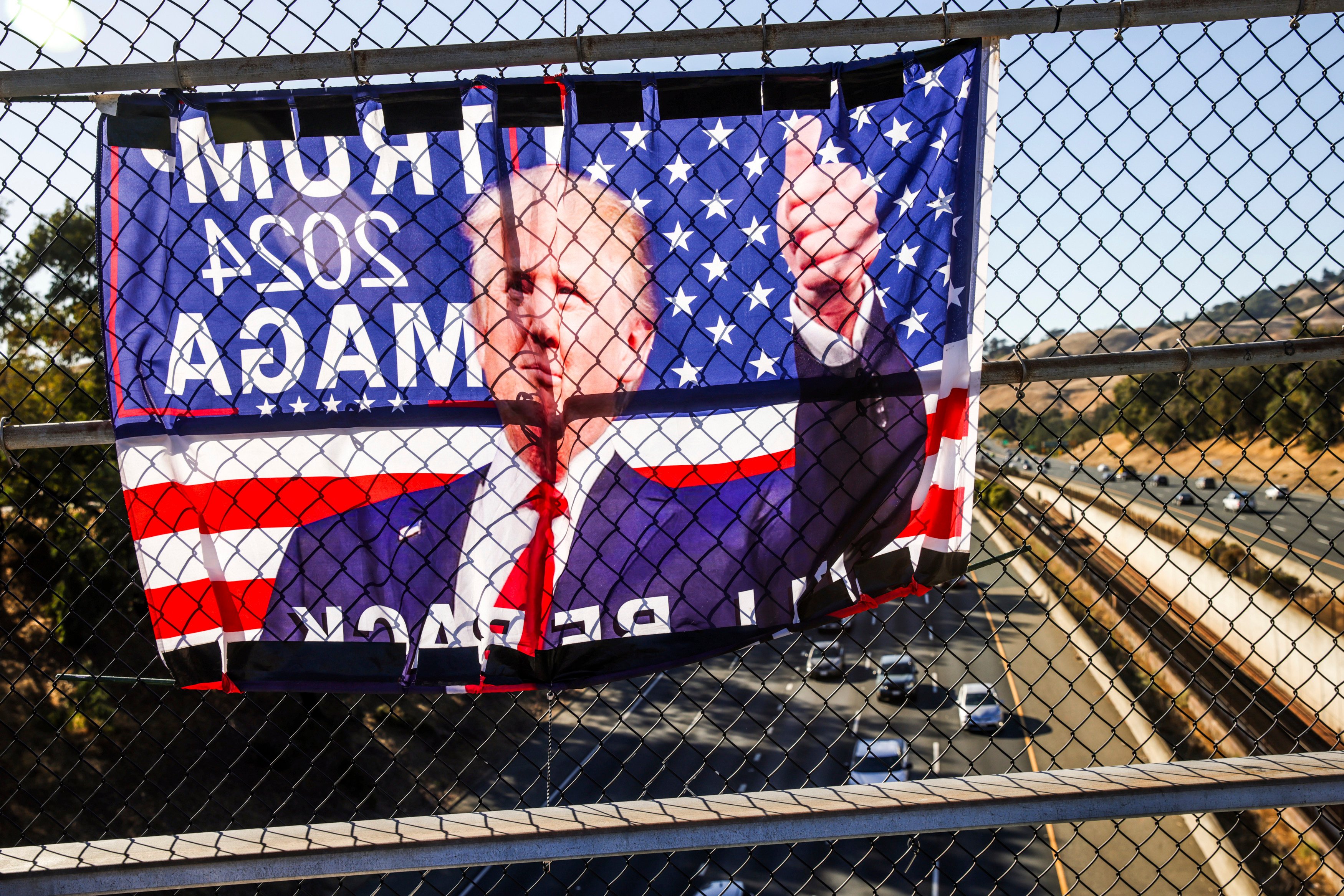 A Trump flag hangs on a fence at the El Curtola Boulevard overpass in Lafayette, California, on November 6. Photo: San Francisco Chronicle via AP