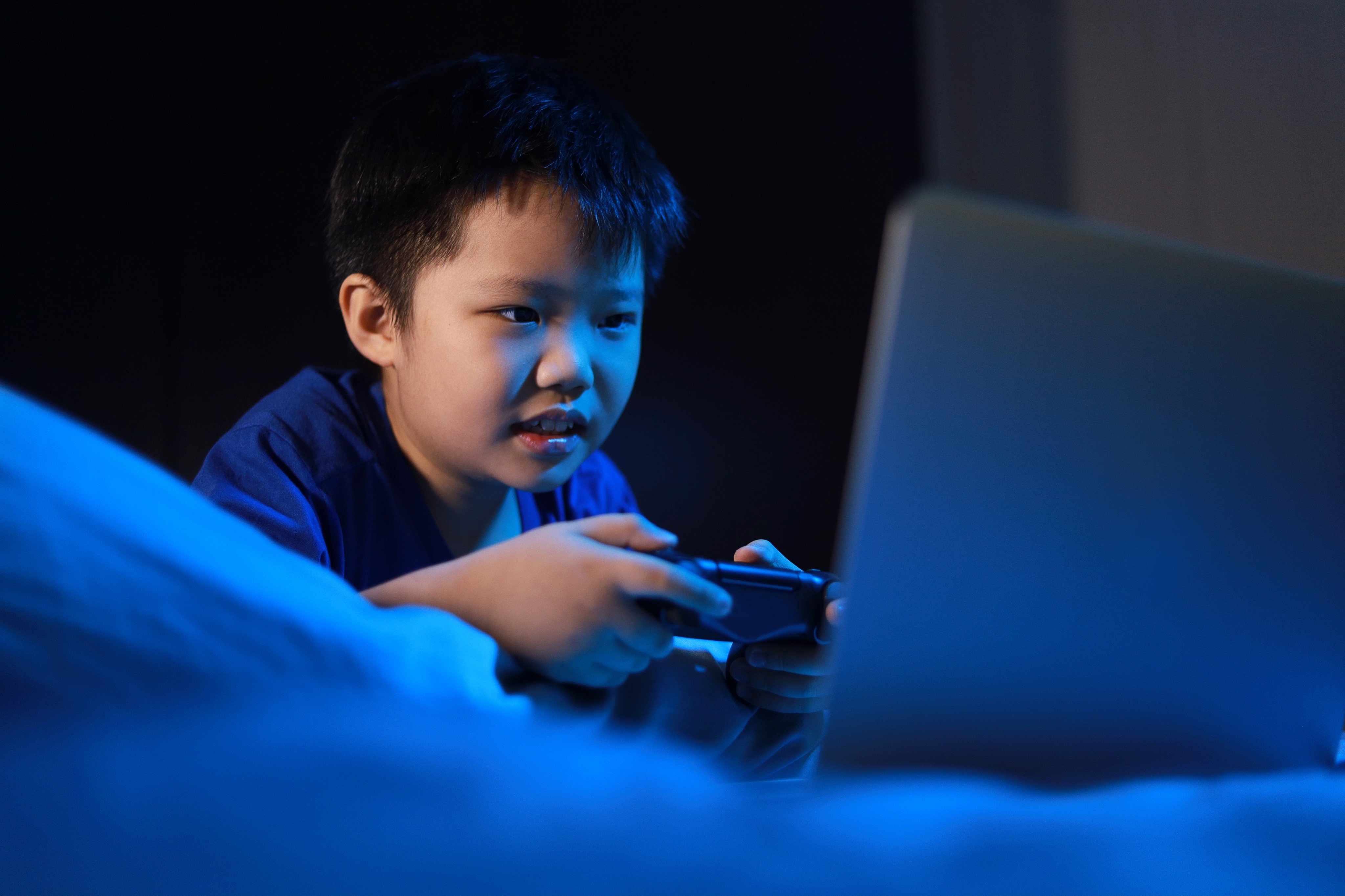 A boy plays a video game in a dark bedroom. An expert explains what sorts of video games preschoolers can play, which genres are off-limits, what gaming addiction looks like and what games can teach. Photo: Shutterstock