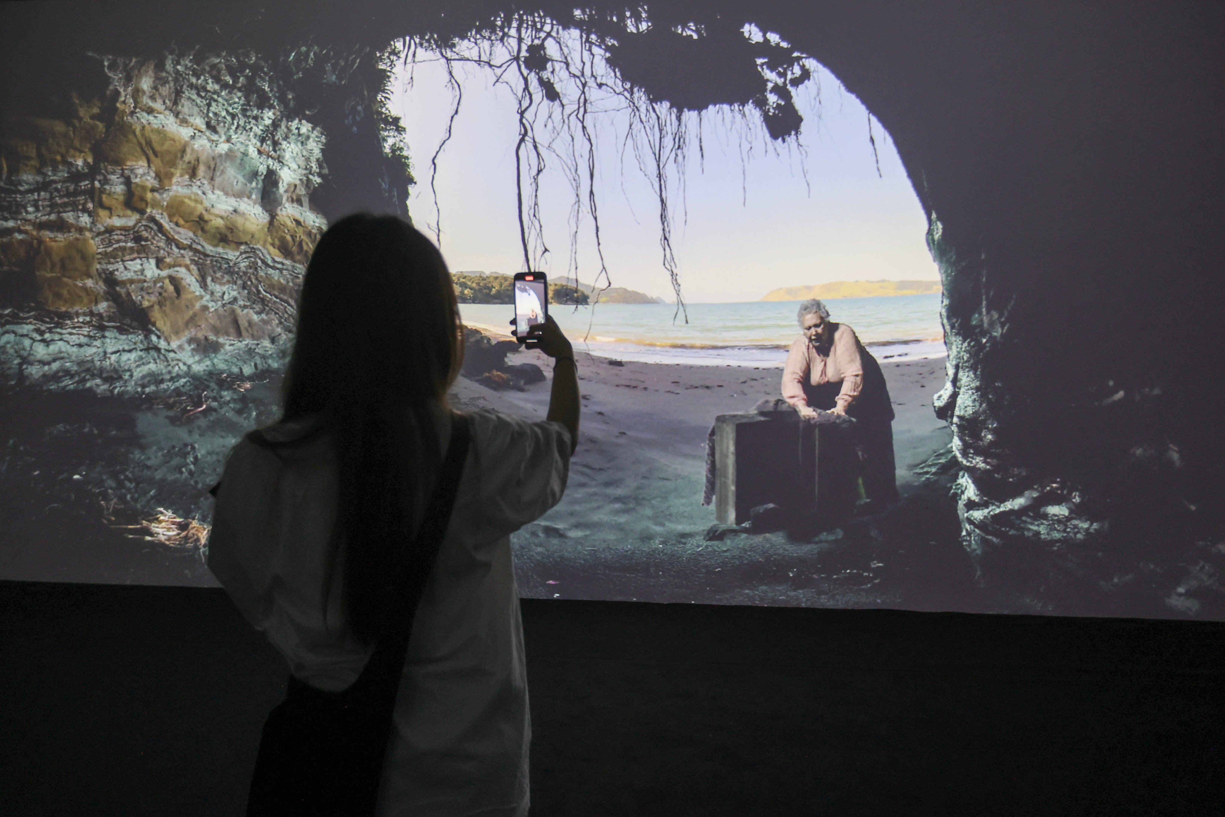 A visitor watches Lisa Reihana’s DigiRadiance: Gold_Lead_Wood_Coal. Photo:  Edmond So