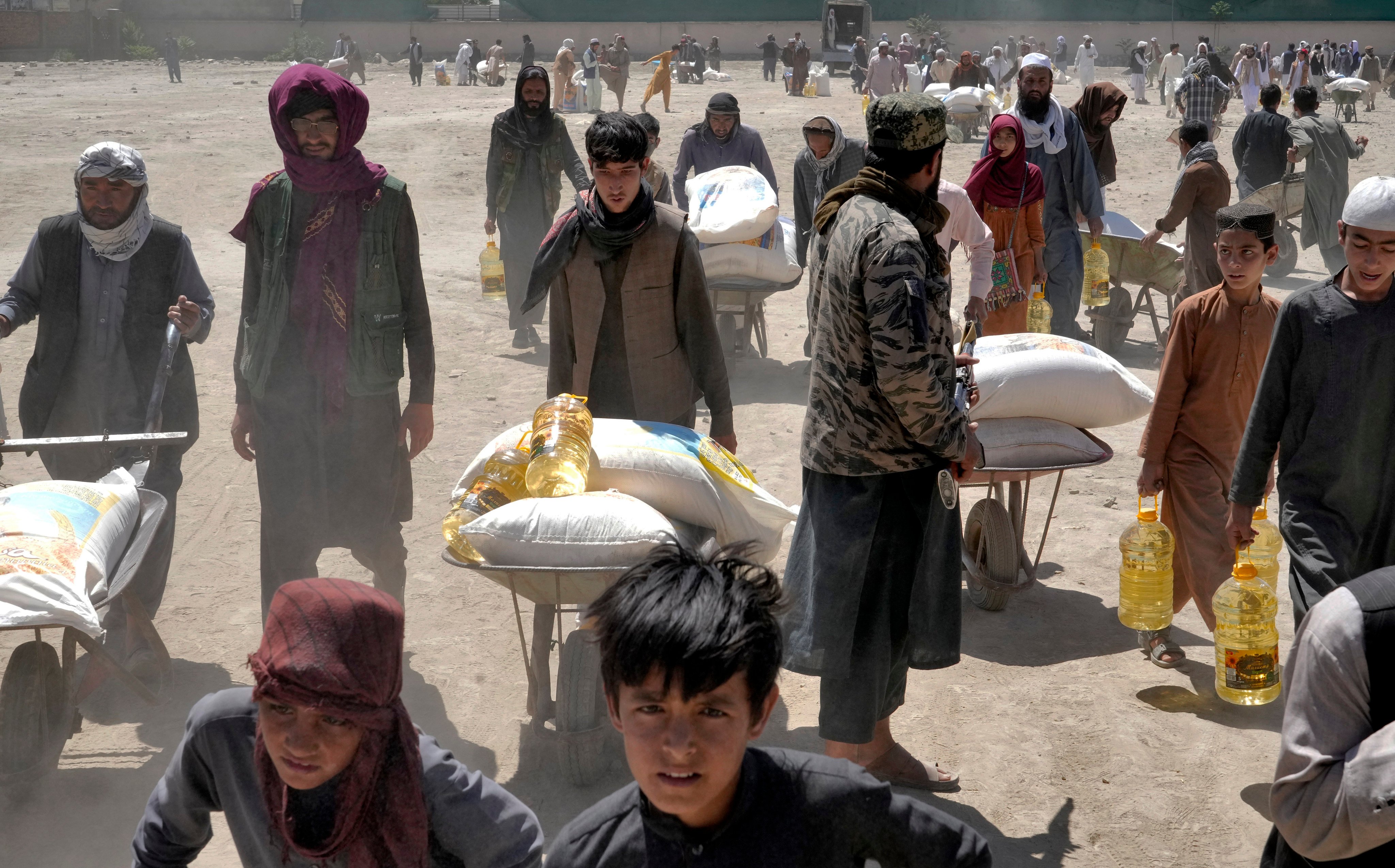 A Taliban fighter stands guard as people receive food rations distributed by a Chinese humanitarian aid group, in Kabul, Afghanistan, on April 30, 2022. Afghanistan also had the highest number of children made homeless by climate disasters of any country as of the end of 2023, according to an August report from international aid agency Save the Children. Photo: AP