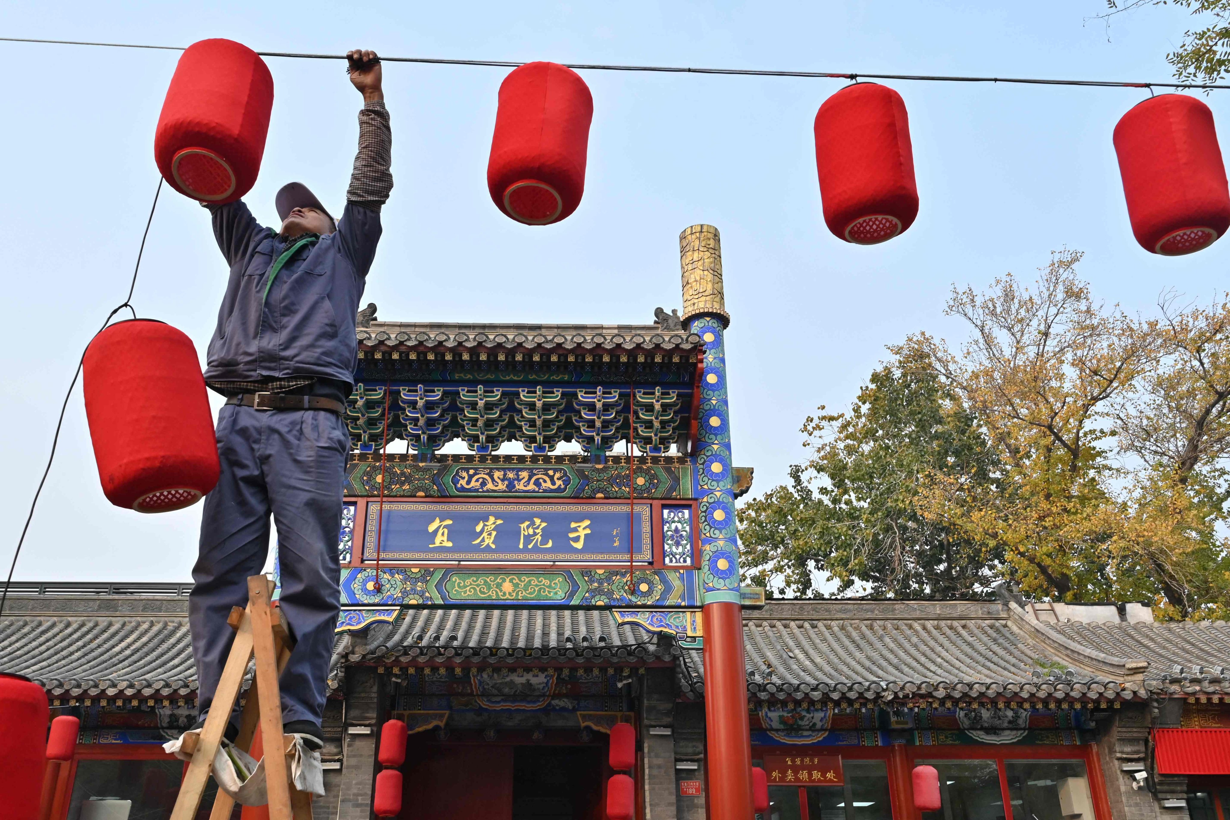 A man installs lanterns outside a newly opened restaurant in Beijing. Photo: AFP