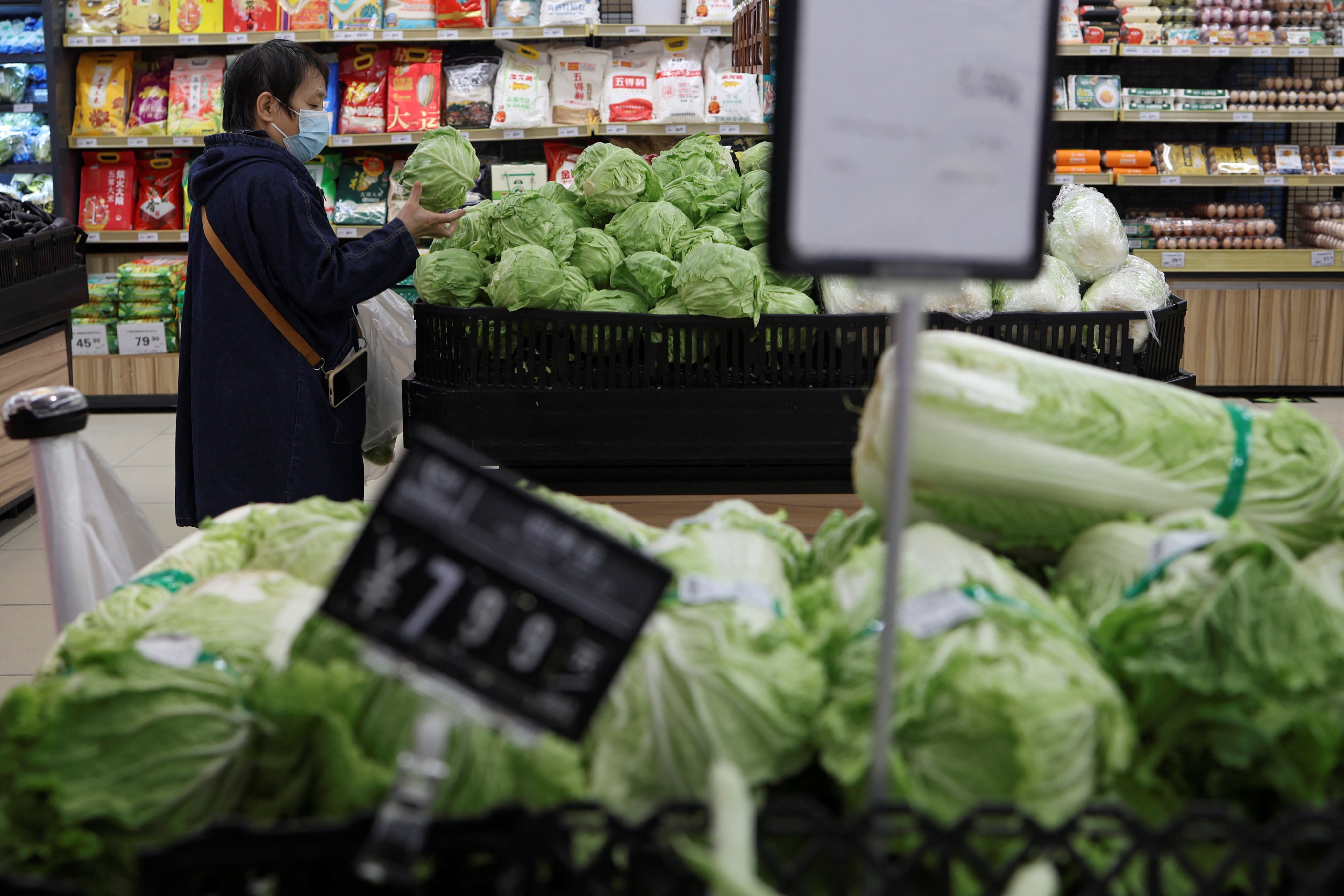 A customer shops for cabbages at the vegetable section of a supermarket in Beijing. Photo: Reuters