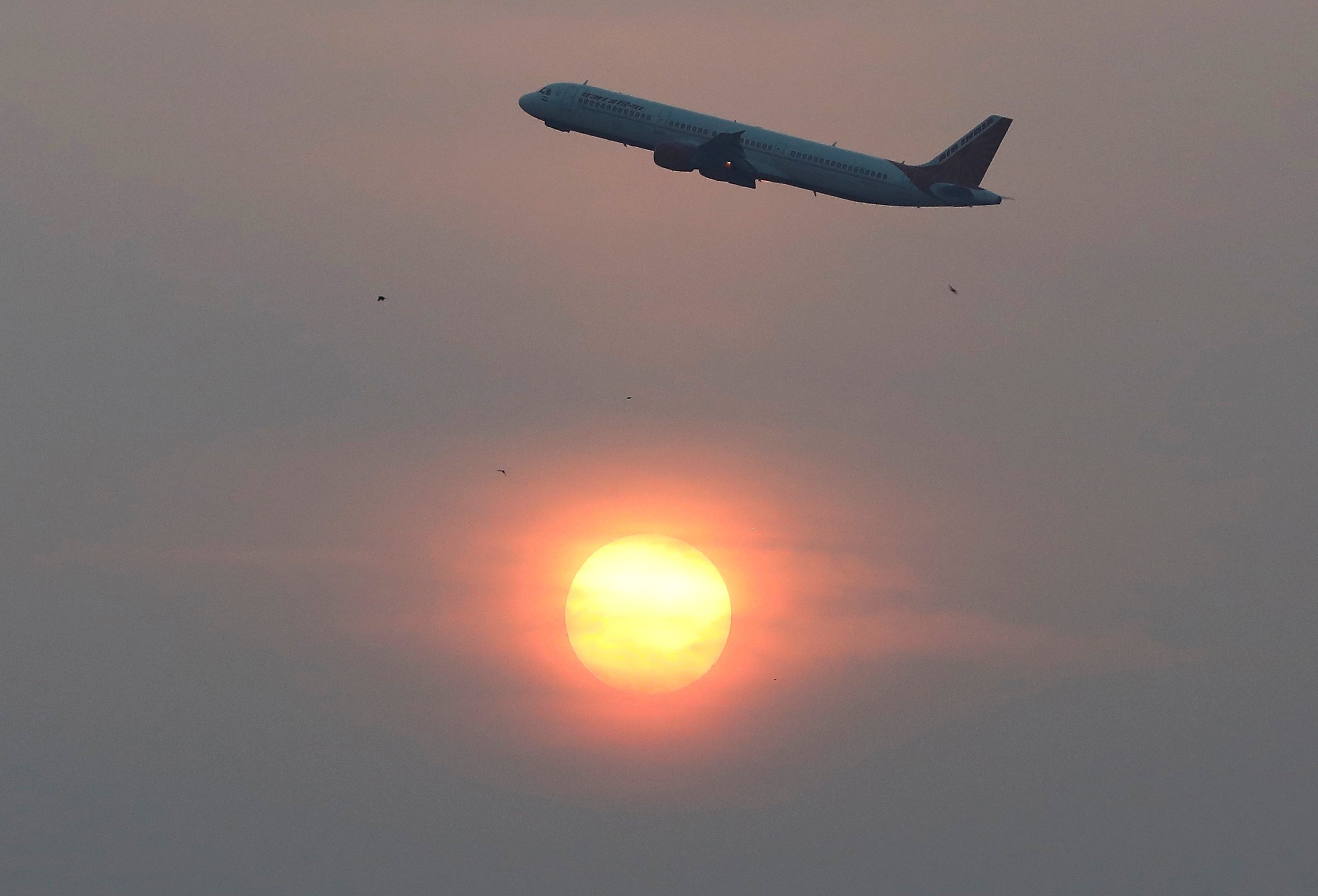 An Air India plane passes the sun after take-off in Ahmedabad, India. Photo: Reuters