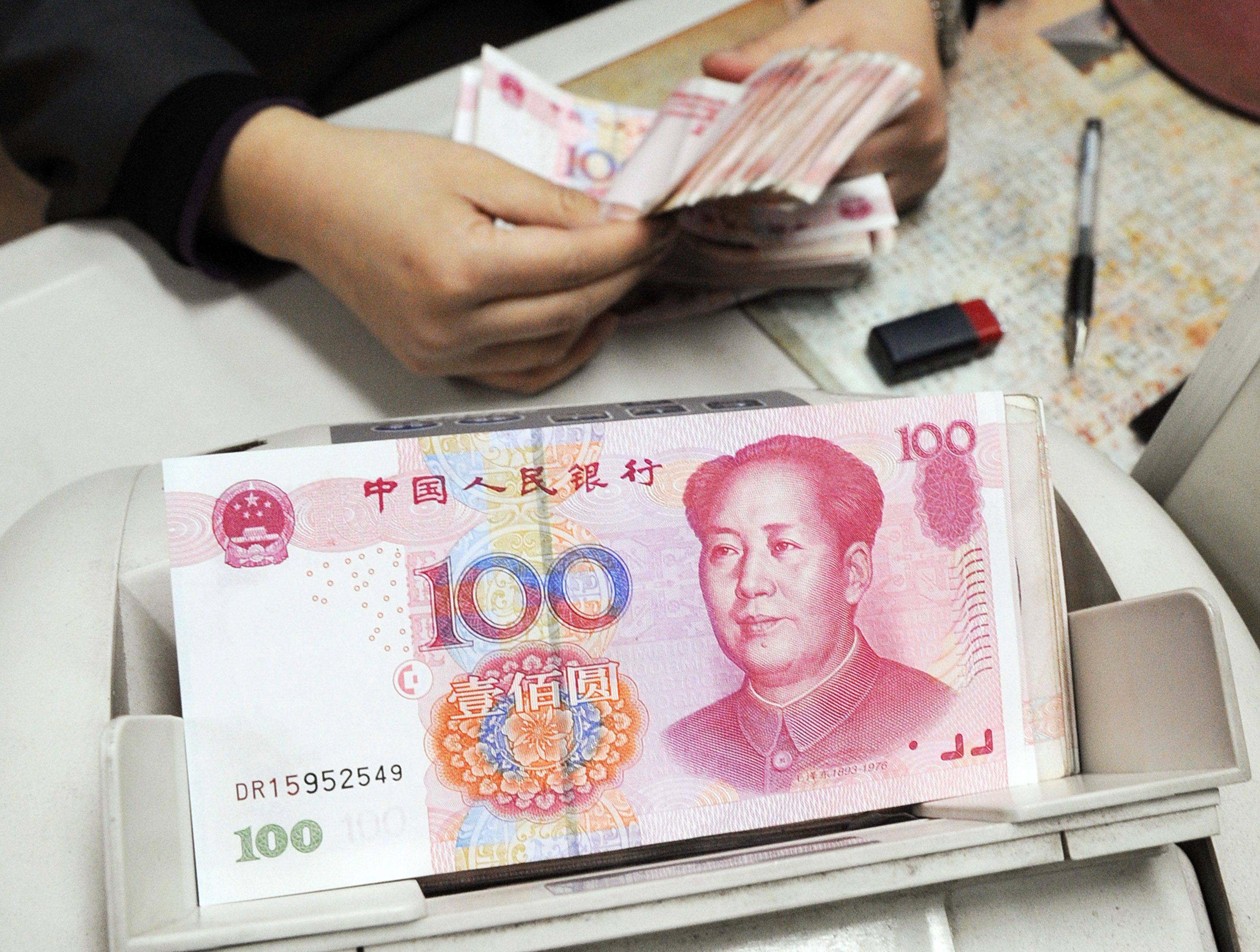 A Chinese bank teller counting yuan notes at a bank in Shanghai. Photo: AFP