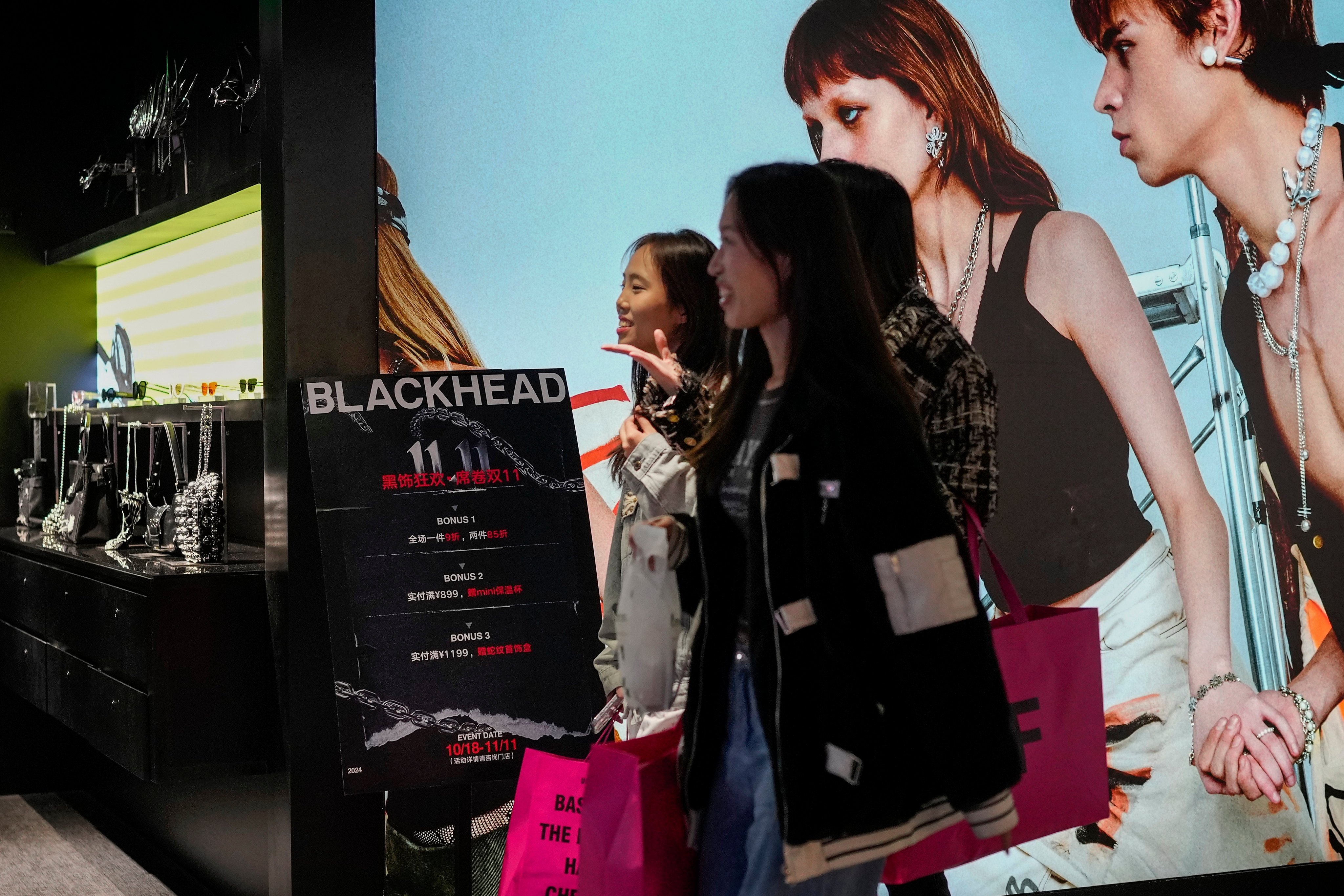 Women walk inside a fashion accessories store displaying Singles’ Day discounts at a Beijing shopping centre on November 11, 2024. Photo: AP